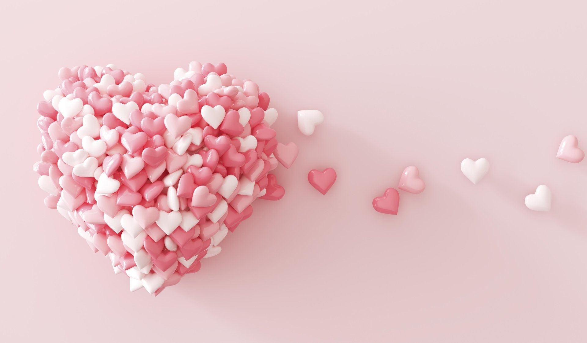 A heart-shaped arrangement of small pink and white hearts on a soft pink background, perfect for Valentine's Day