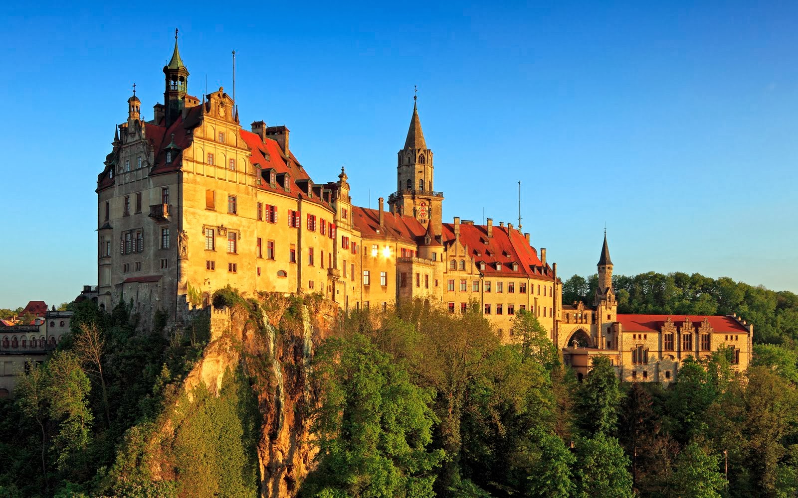A majestic castle perched atop a cliff, bathed in the warm glow of the setting sun