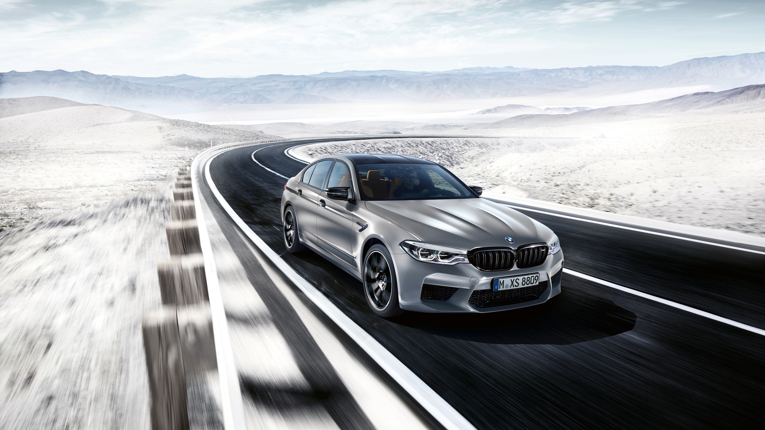 Silver BMW M5 speeding down a desert highway