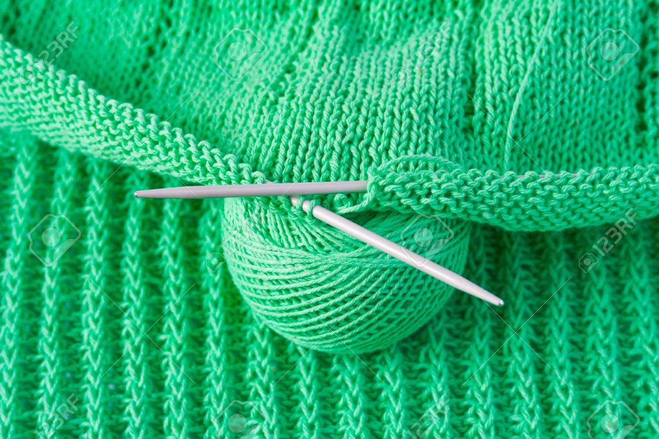 Green Cotton Yarn With Knitting Needles And A Tangle Of