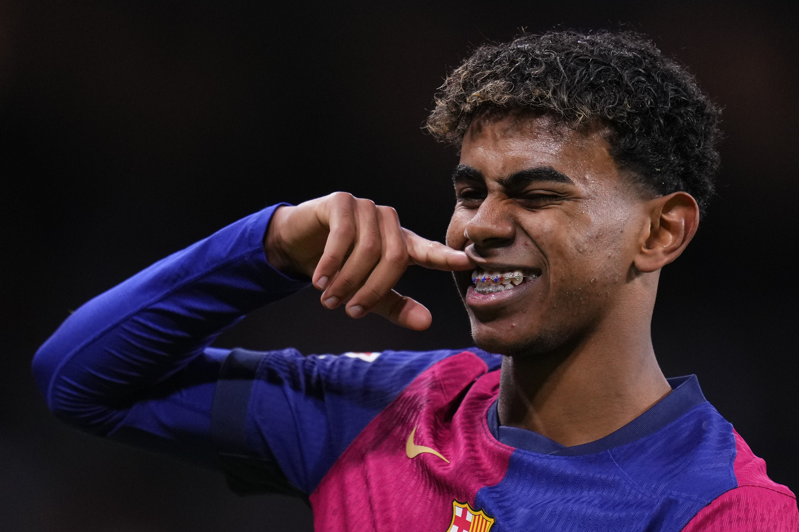 Lamine Yamal of FC Barcelona smiles and points to his braces during a match