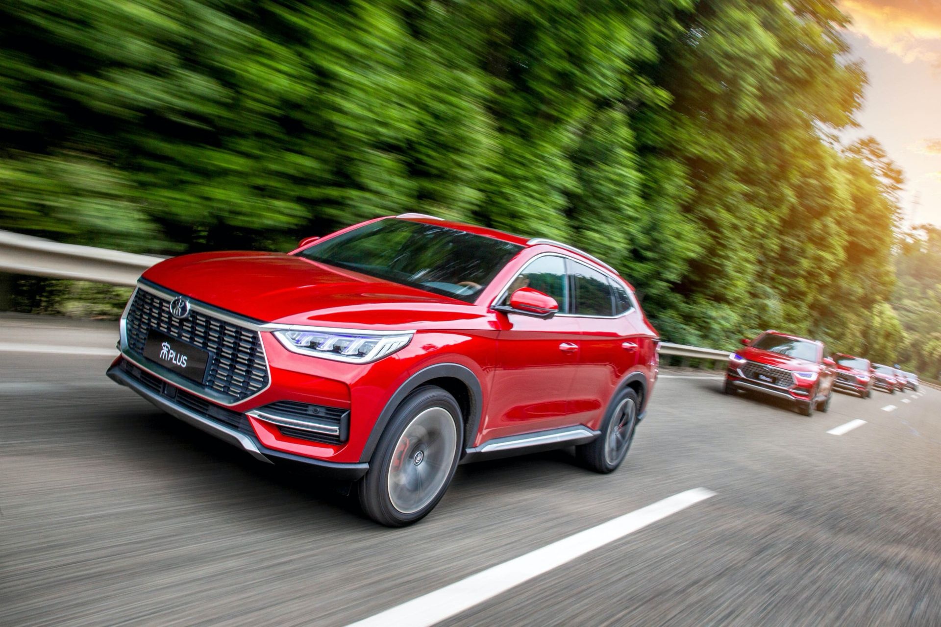 A red BYD Song Plus DM-i SUV driving on a highway, showcasing its sleek design and dynamic performance