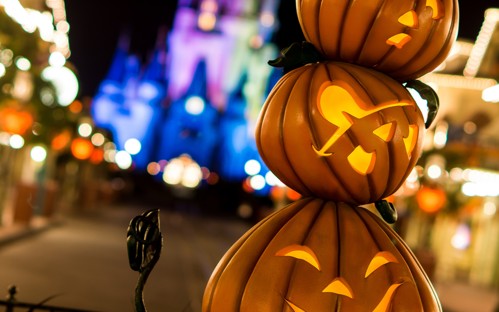 Stack of three carved and lit Jack-o'-lanterns with blurred Cinderella Castle in the background at Mickey's Not-So-Scary Halloween Party at Walt Disney World
