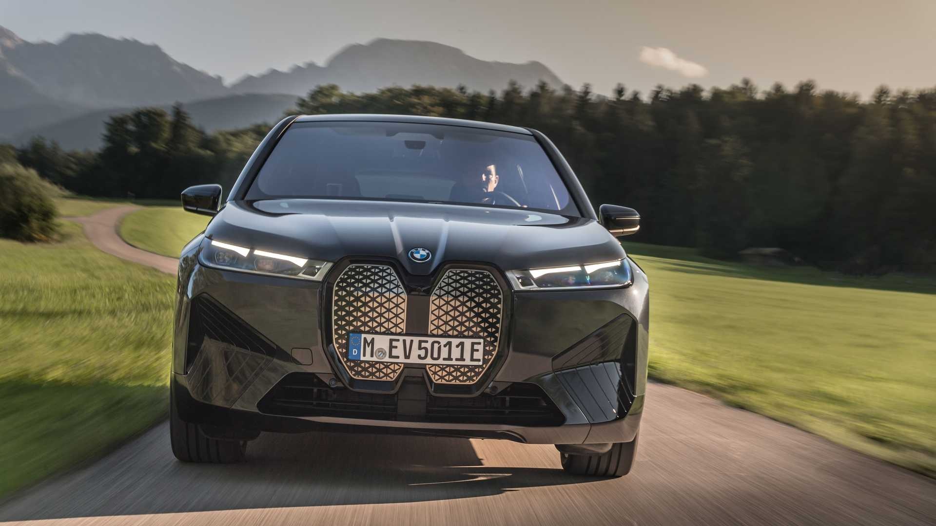 A BMW iX electric SUV driving on a scenic road