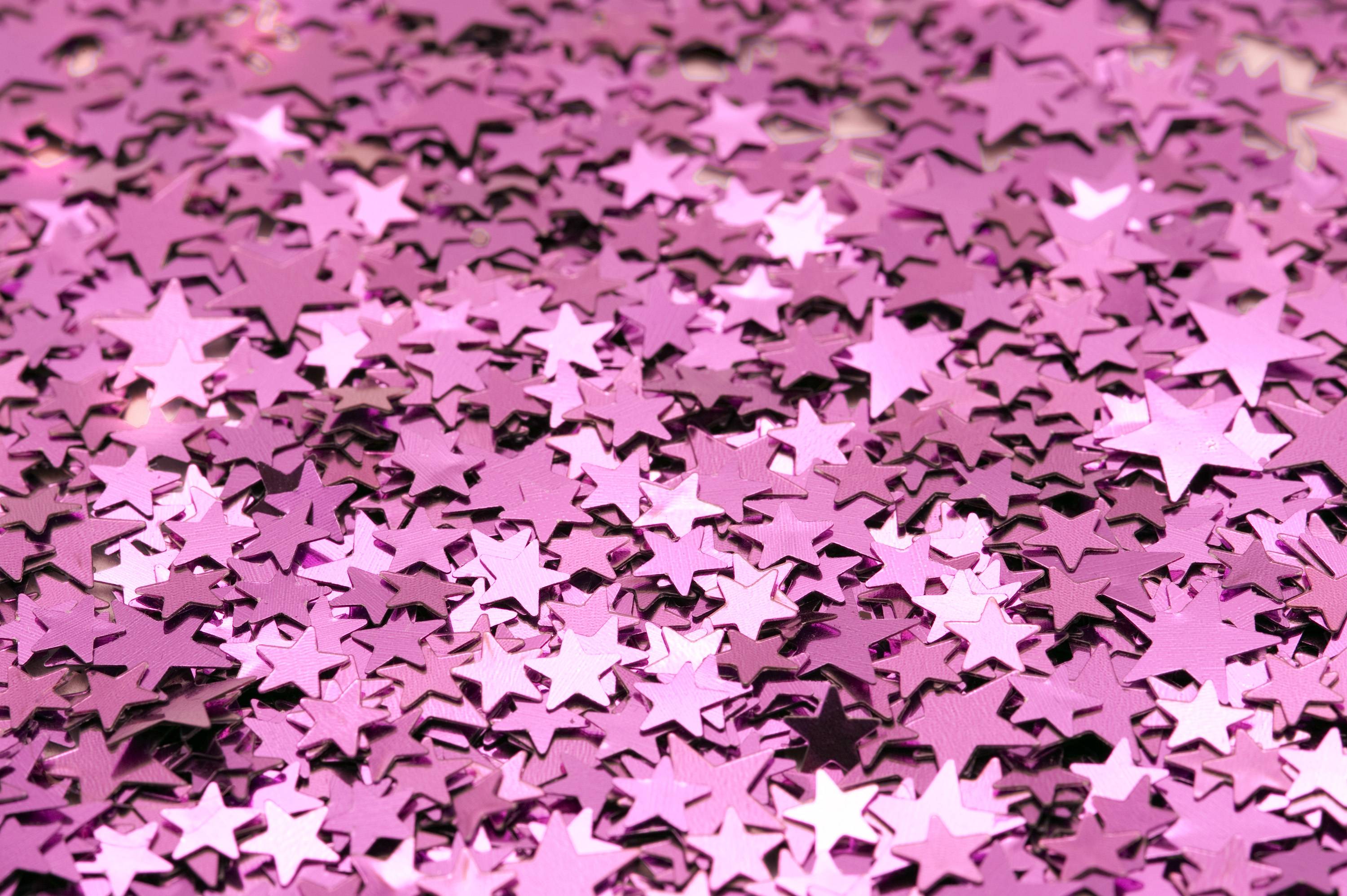 Close-up of shimmering pink glitter stars, creating a festive and sparkly background