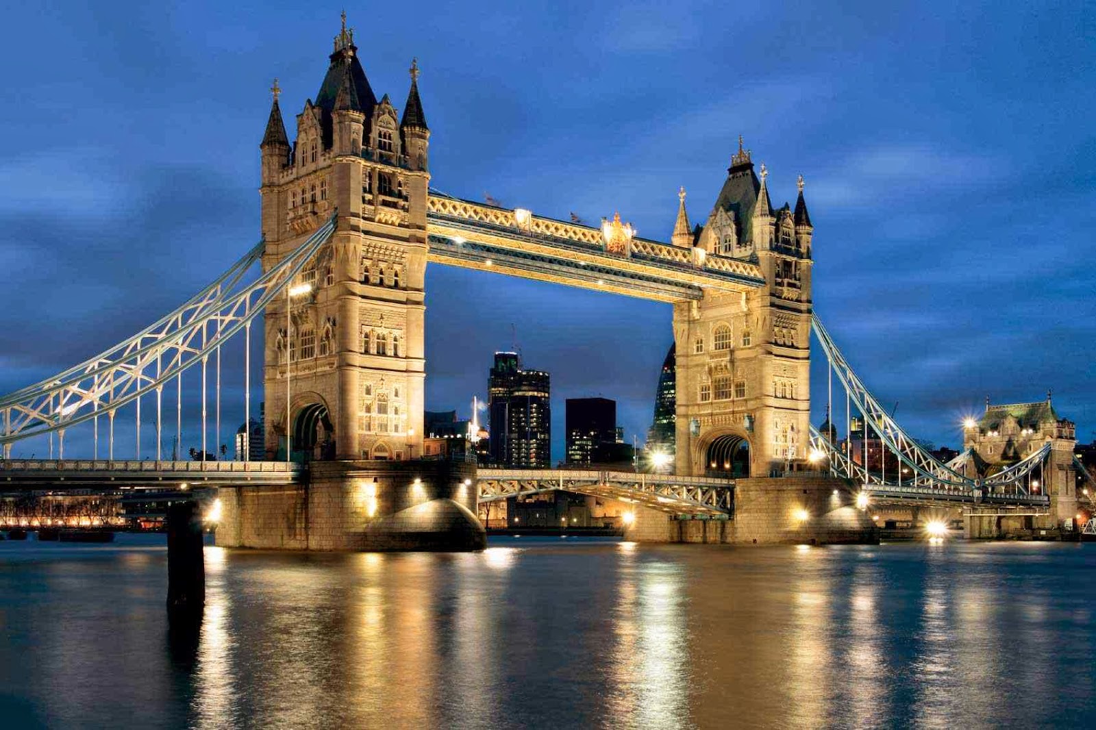 Tower Bridge in London at night, lit up and reflecting in the Thames River