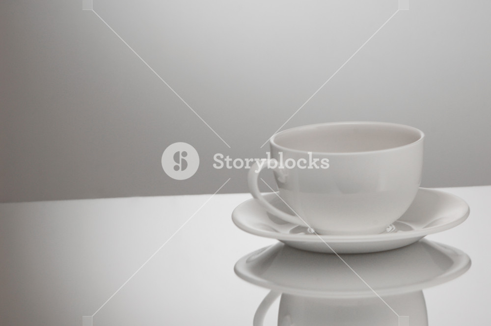 One White Cup And Saucer On A Light Background With Reflection