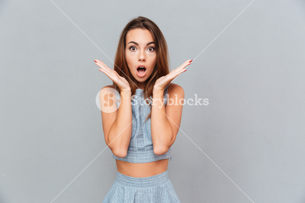 Surprised Shocked Young Woman Standing With Opened Mouth Over Grey