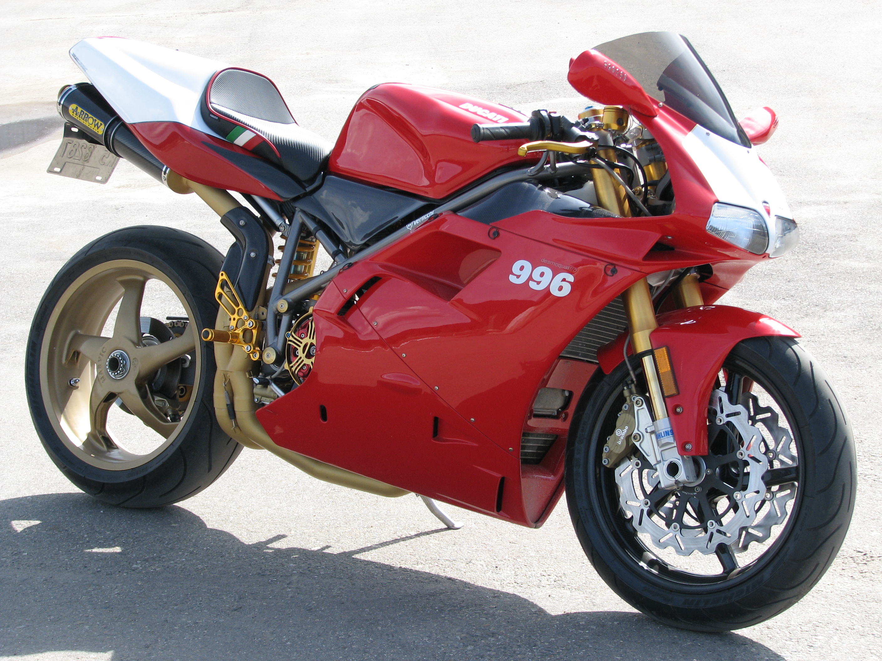 A Ducati 996 sportbike with custom red and white paint job, gold accents, and aftermarket parts