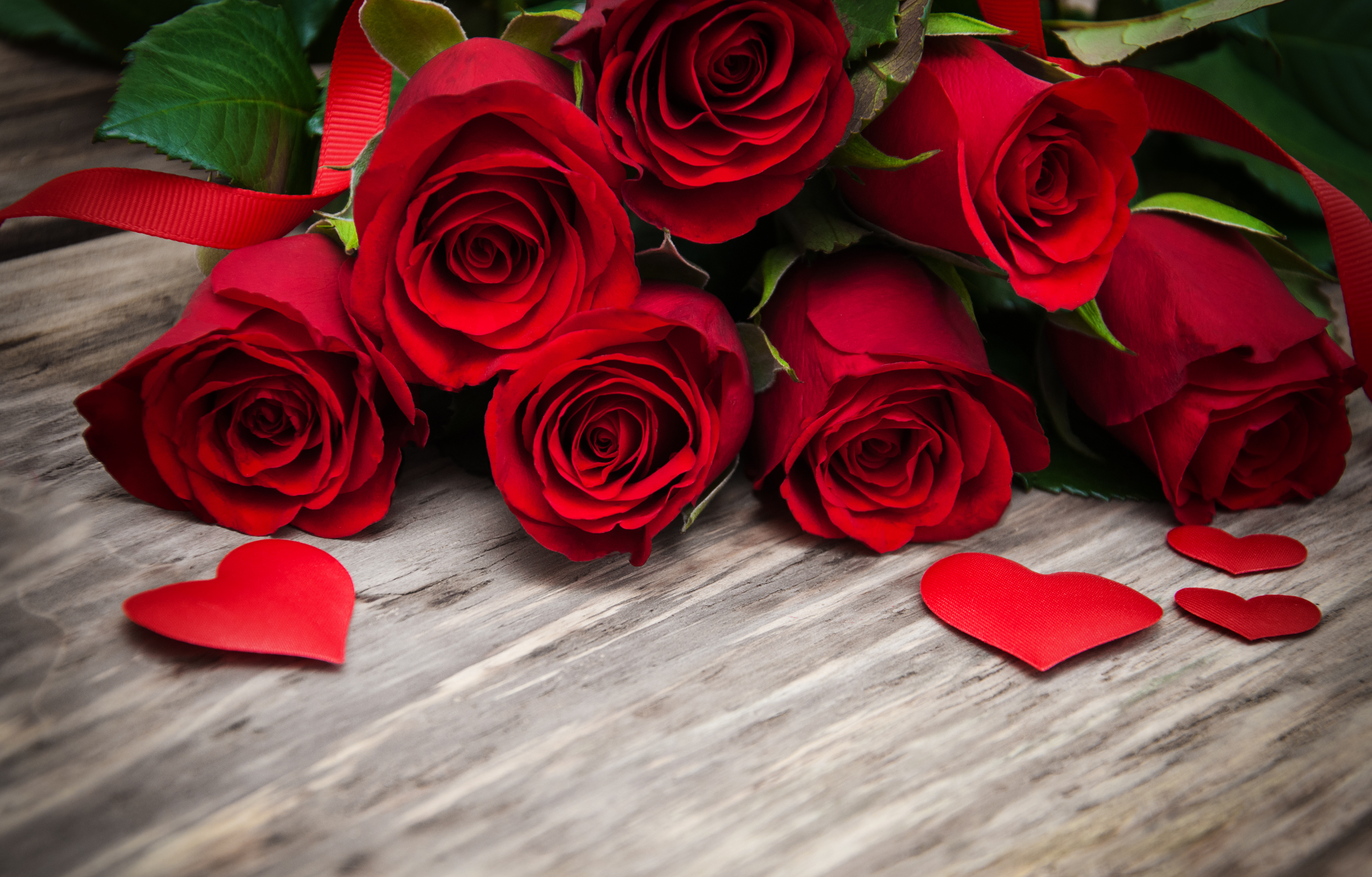 Red roses and hearts on a wooden background, perfect for Valentine's Day
