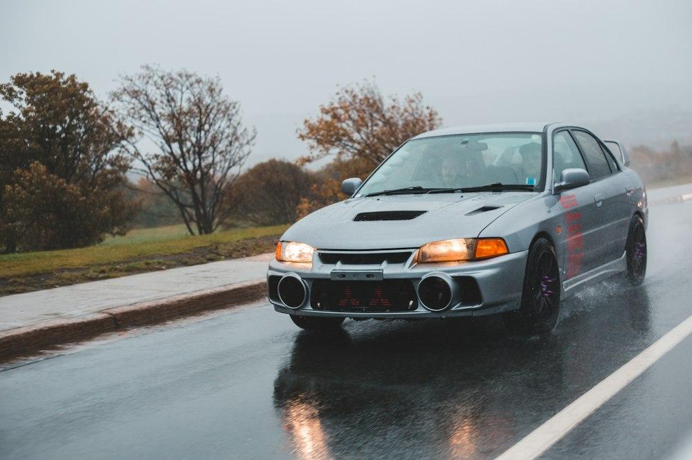 Silver Mitsubishi Sedan Travelling In The Wet Road Photo