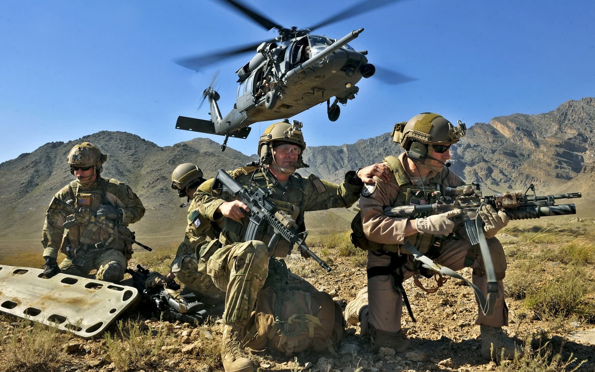 Military personnel securing a landing zone for a helicopter in a mountainous region