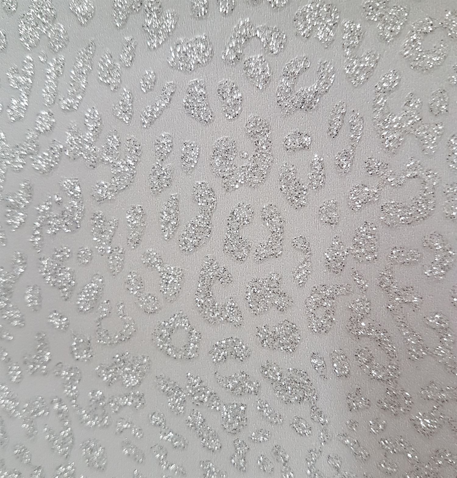 Close-up of a silver glitter leopard print on a light gray background, showcasing the sparkling texture and pattern detail