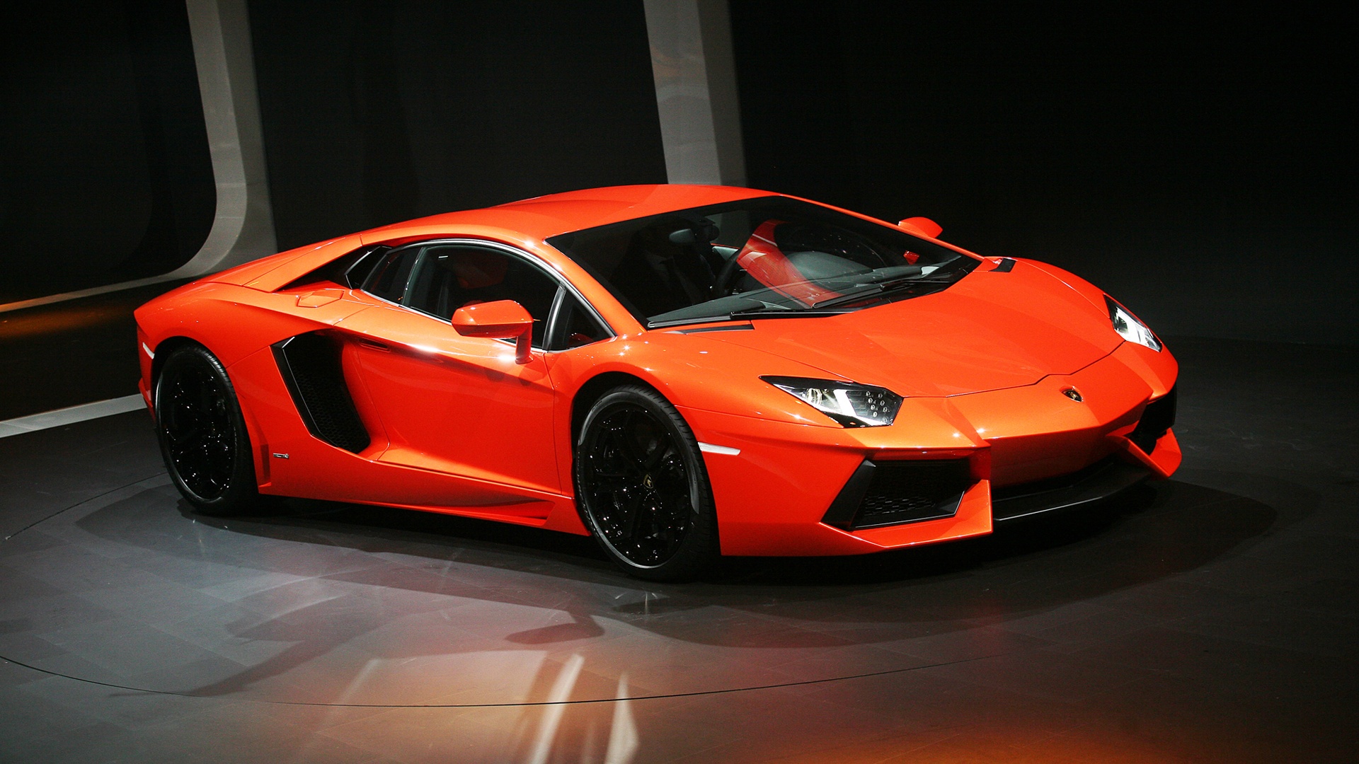 A vibrant orange Lamborghini Aventador sports car on display at a car show