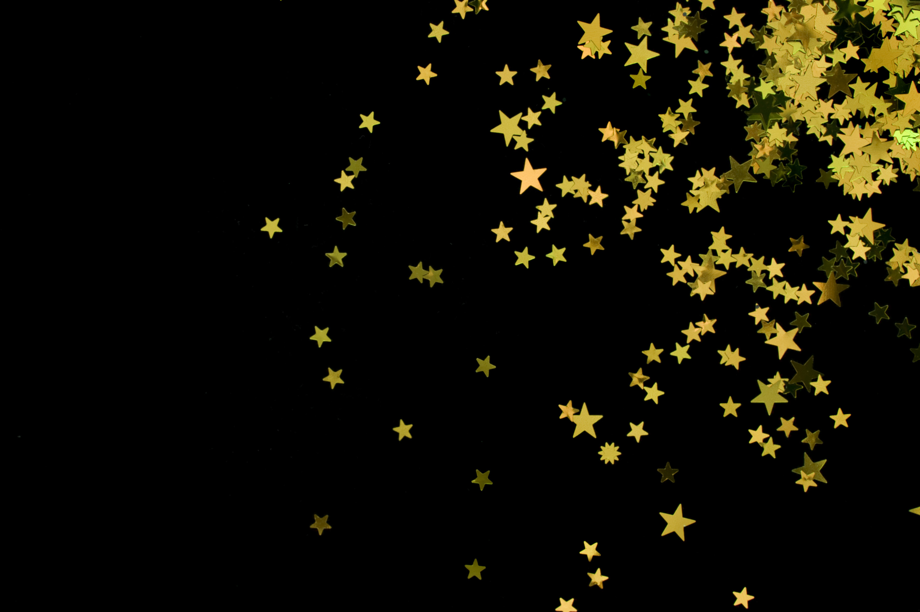  scattering of yellow coloured glitter star shapes on a black backdrop