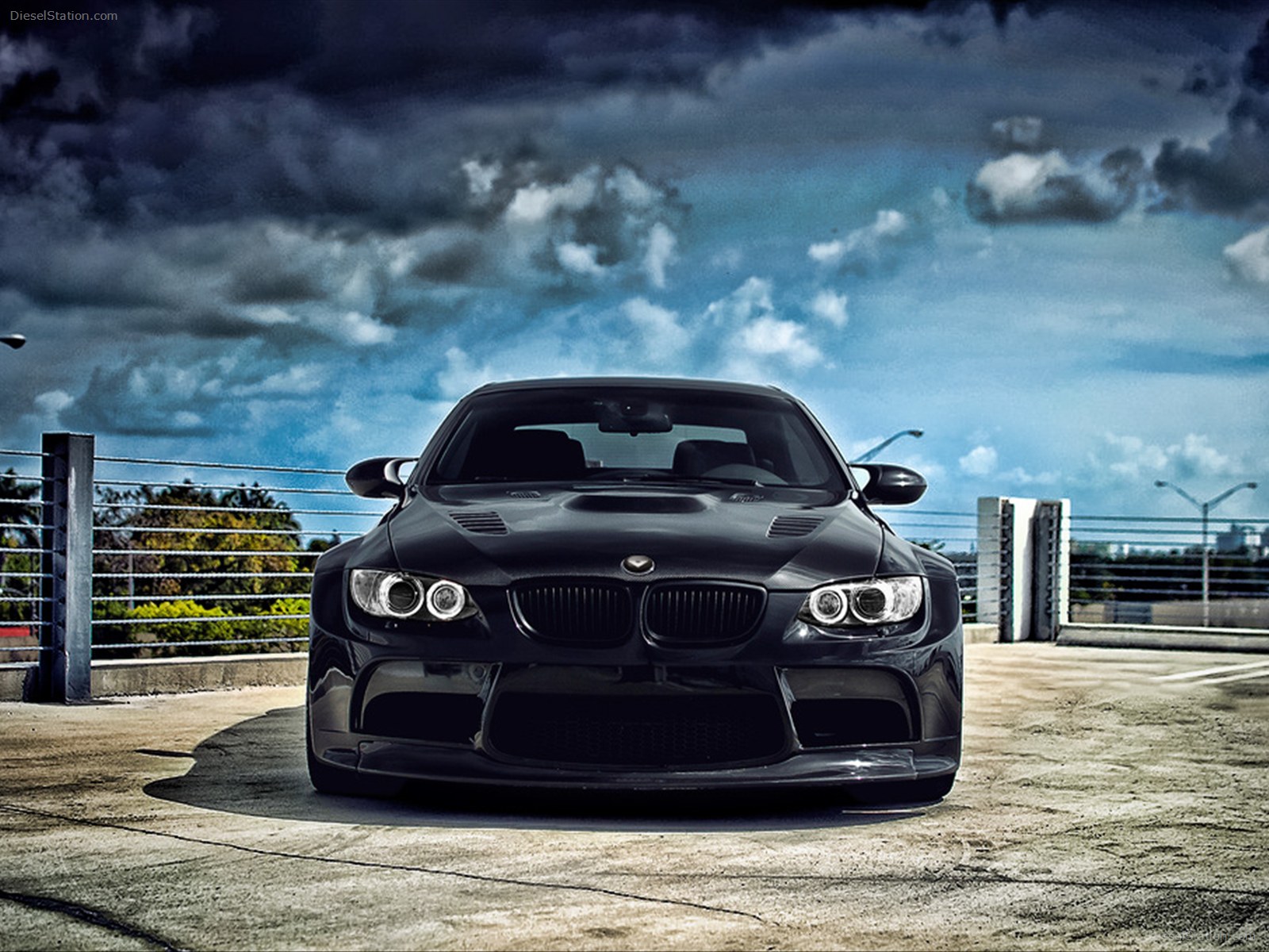 Black BMW M3 parked on a rooftop under a cloudy sky