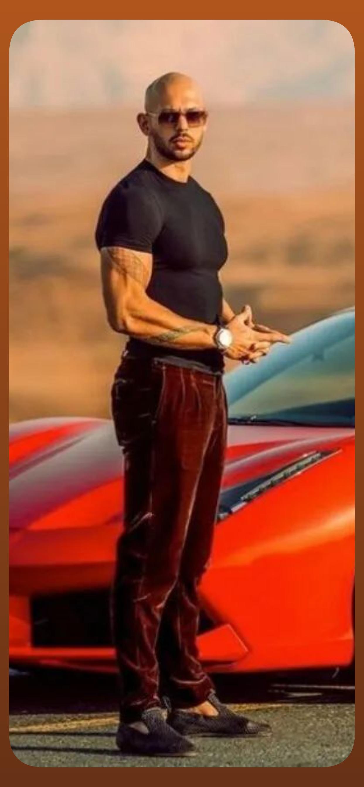 Andrew Tate posing in front of a red sports car in the desert