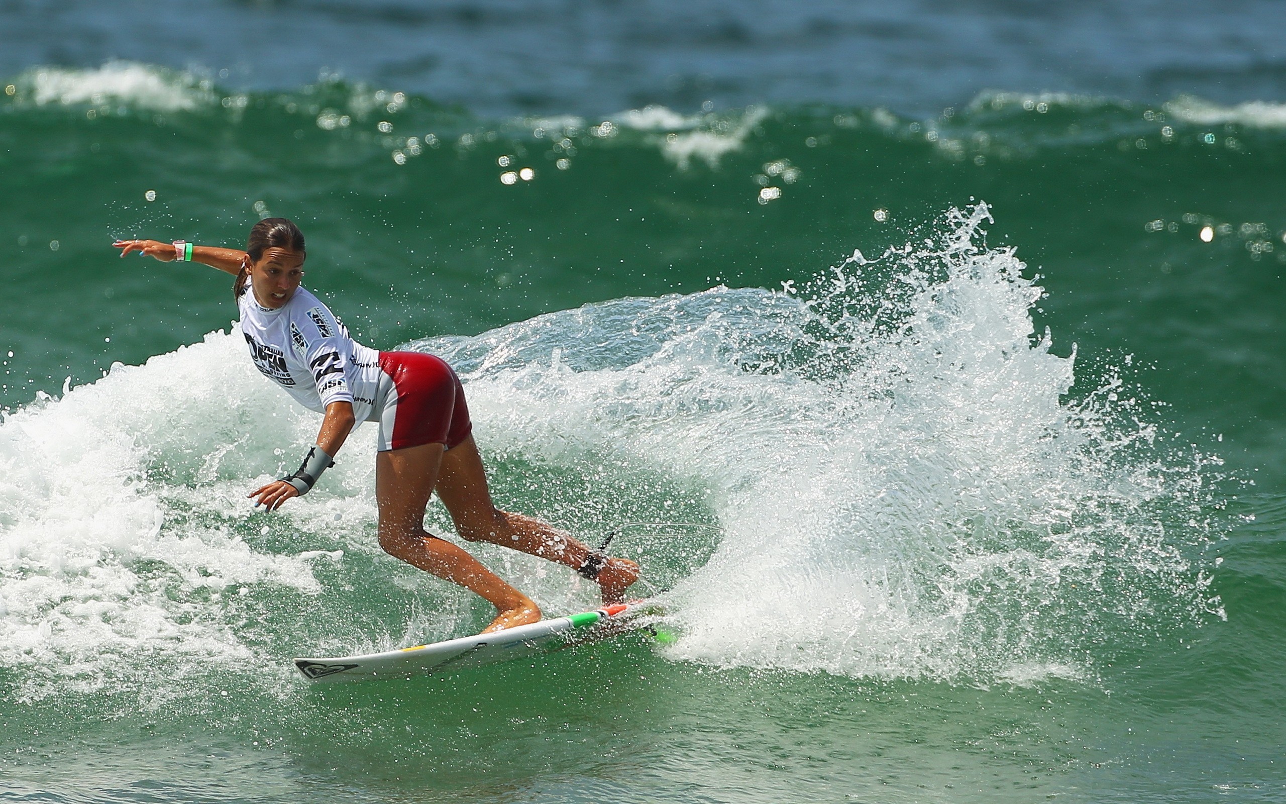 A female surfer carves a wave in a dynamic surfing action shot