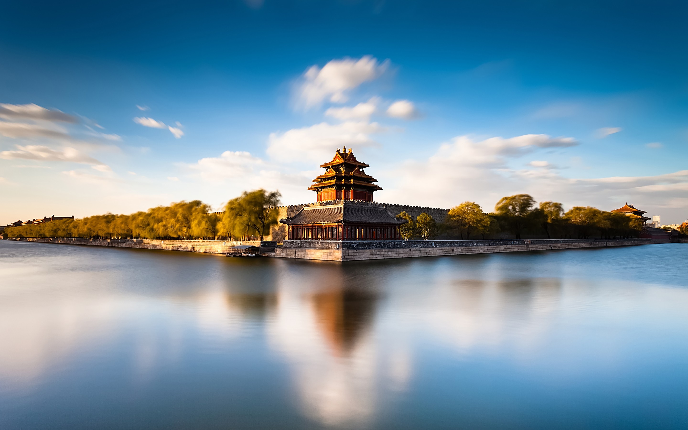 A serene sunset view of the Forbidden City's corner tower reflected in the moat's still water
