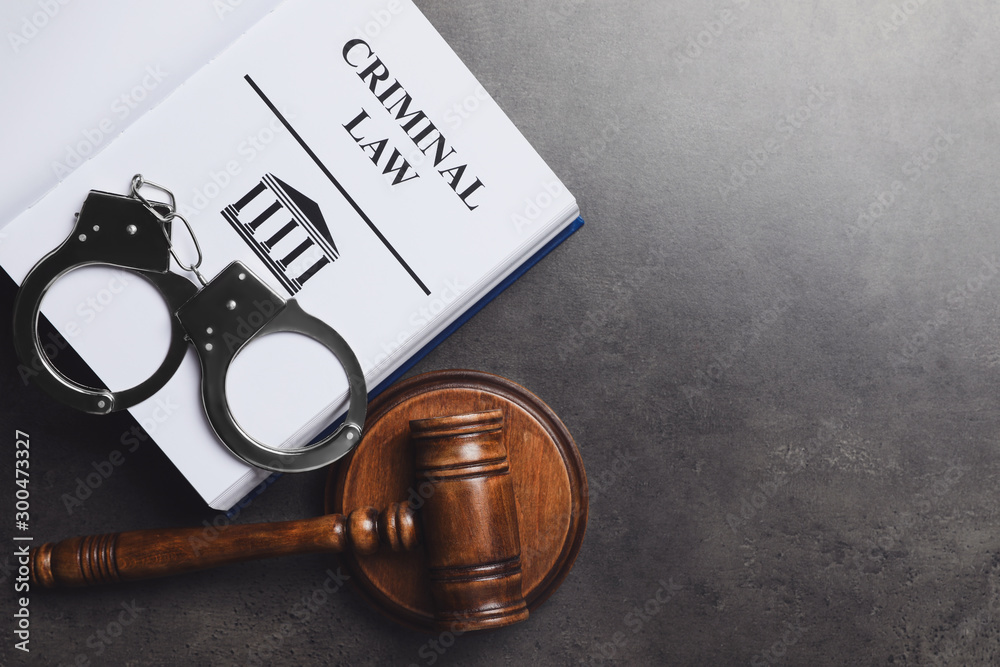 Judges gavel handcuffs and Criminal law book on grey background