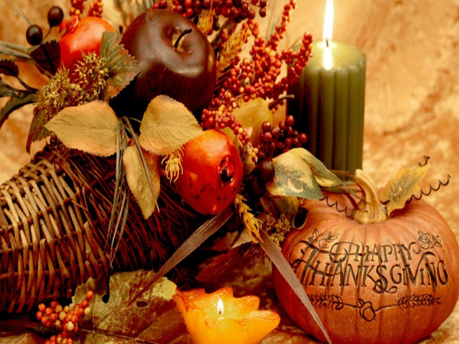 A Thanksgiving still life with a cornucopia, pumpkin, candles, and autumnal fruits and foliage
