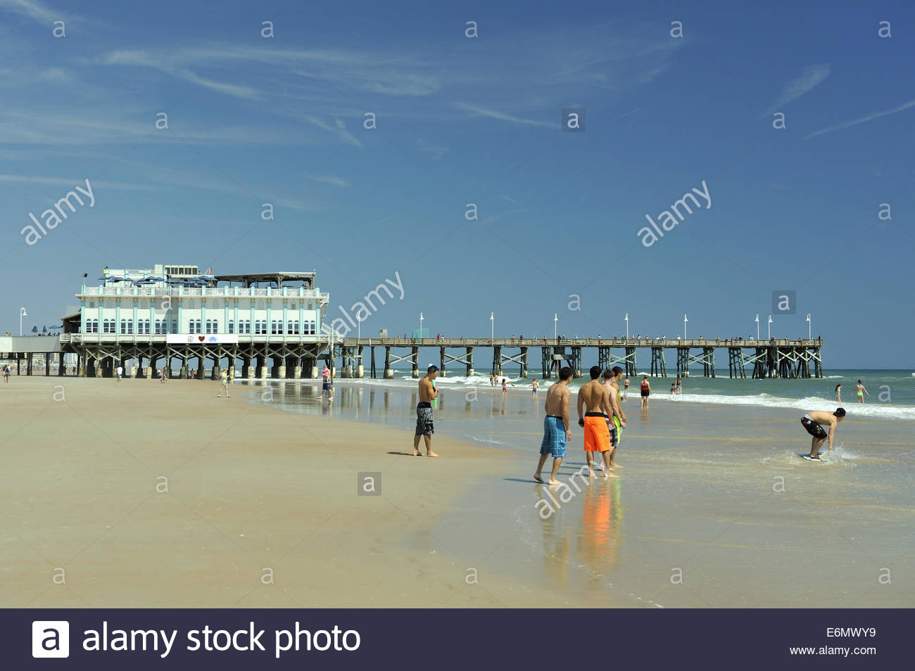 Group Of Teenage Boys Playing On Beach With Daytona Pier In