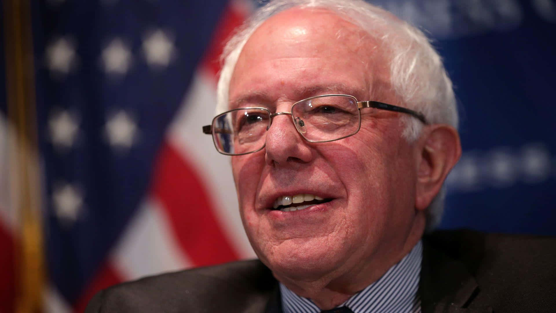 Bernie Sanders Smilingwith American Flag Wallpaper