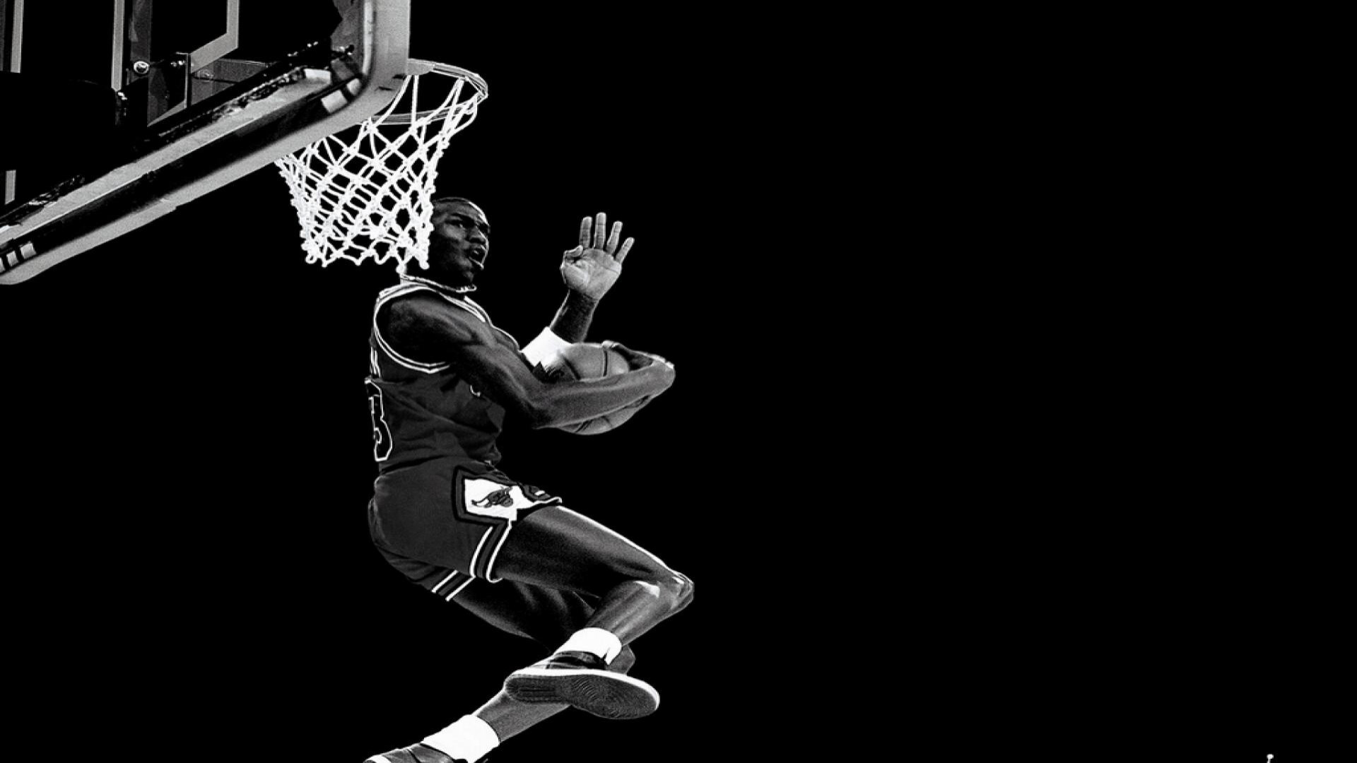 Michael Jordan soars towards the basket for a dunk, showcasing his athleticism in this dynamic black and white image