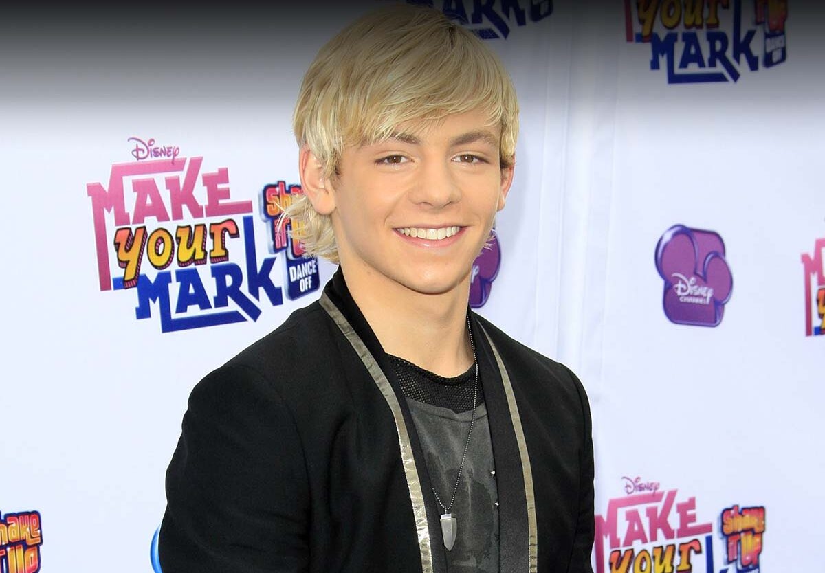 A young man with blond hair smiles at the camera