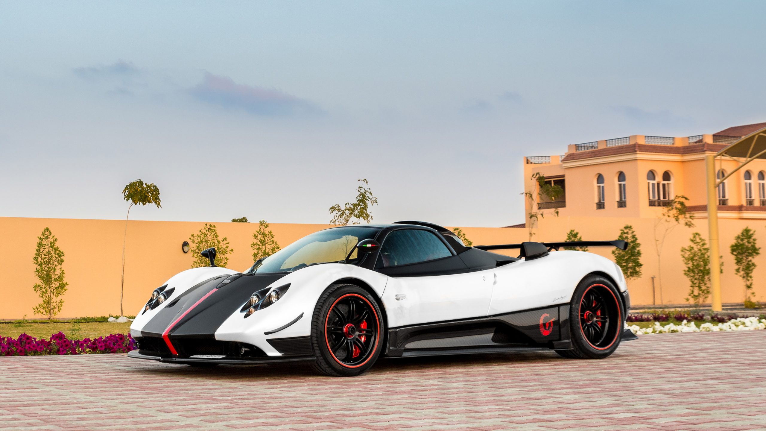 A white and black Pagani Huayra parked in front of a villa