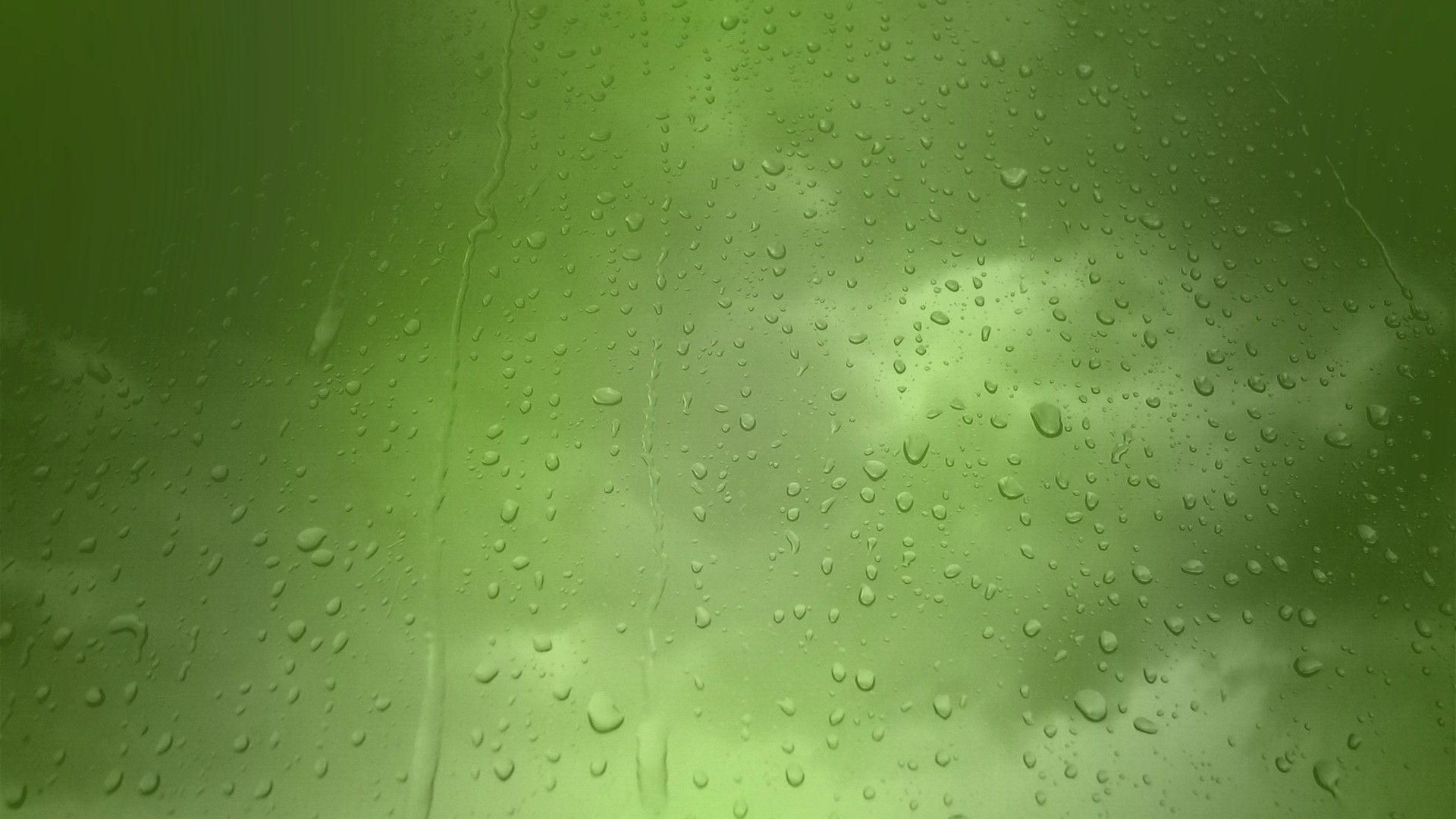 Close-up of raindrops on a window with a minty green background, creating a refreshing and abstract pattern