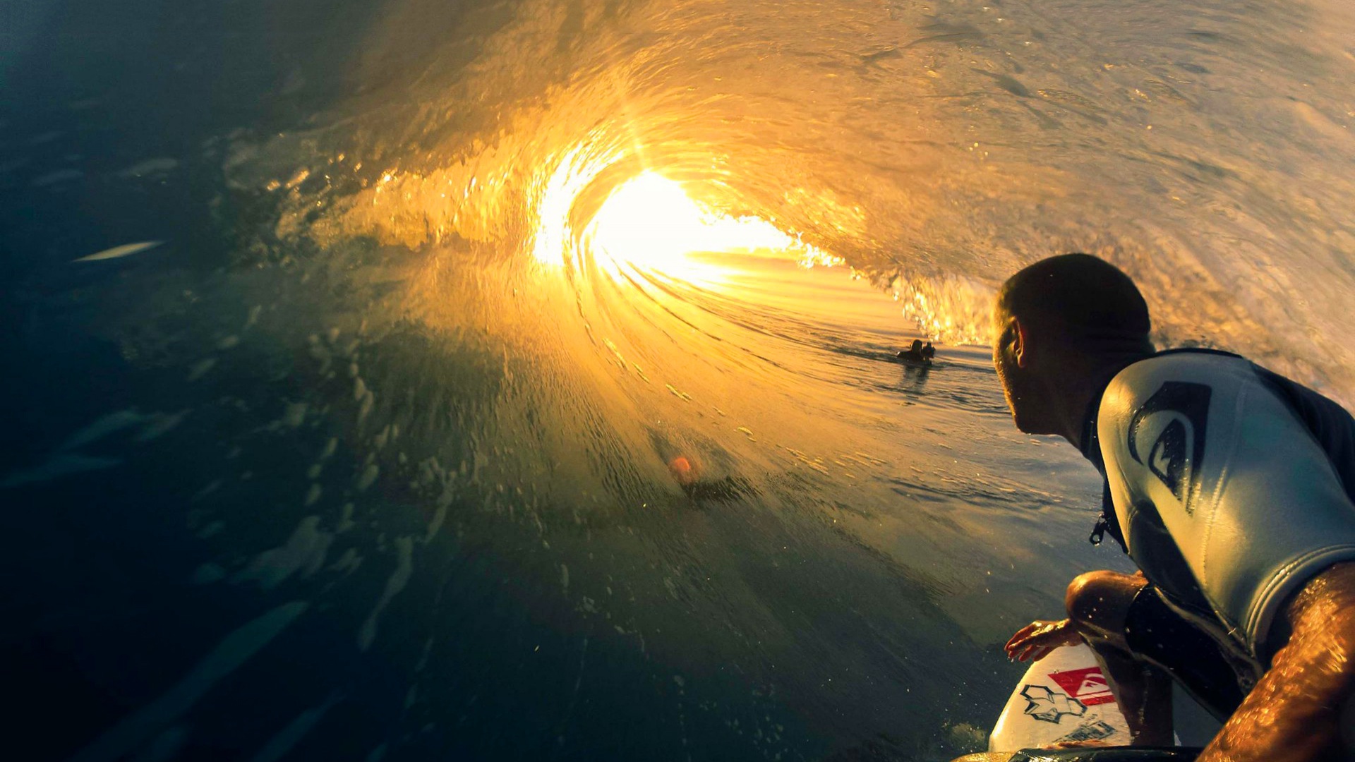 A surfer inside the barrel of a wave at sunset