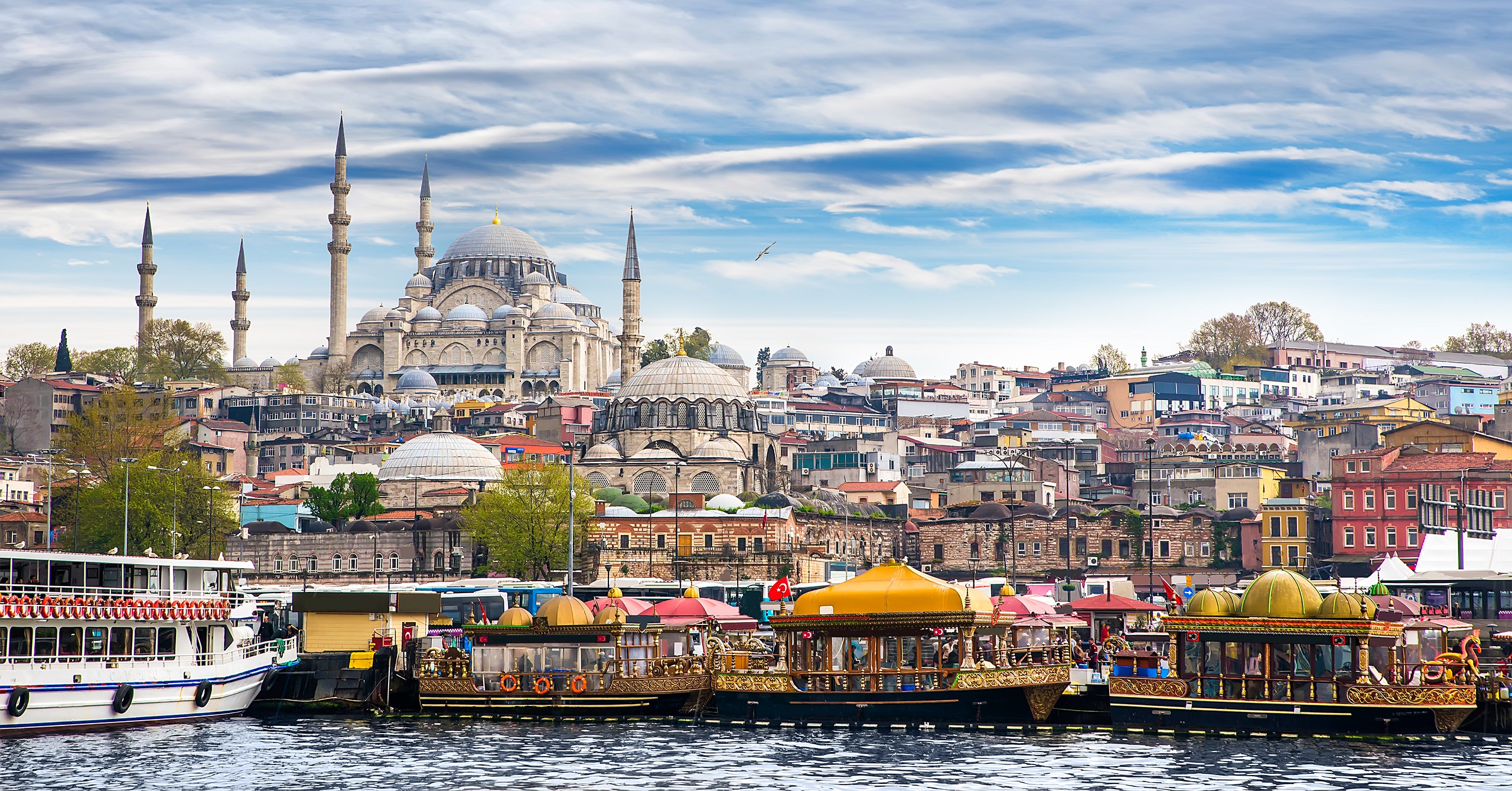A scenic view of Istanbul's skyline featuring the Süleymaniye Mosque and the Golden Horn with traditional boats in the foreground