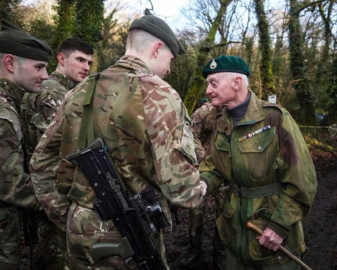 A World War II veteran shakes hands with a modern-day soldier, highlighting the legacy and camaraderie of military service