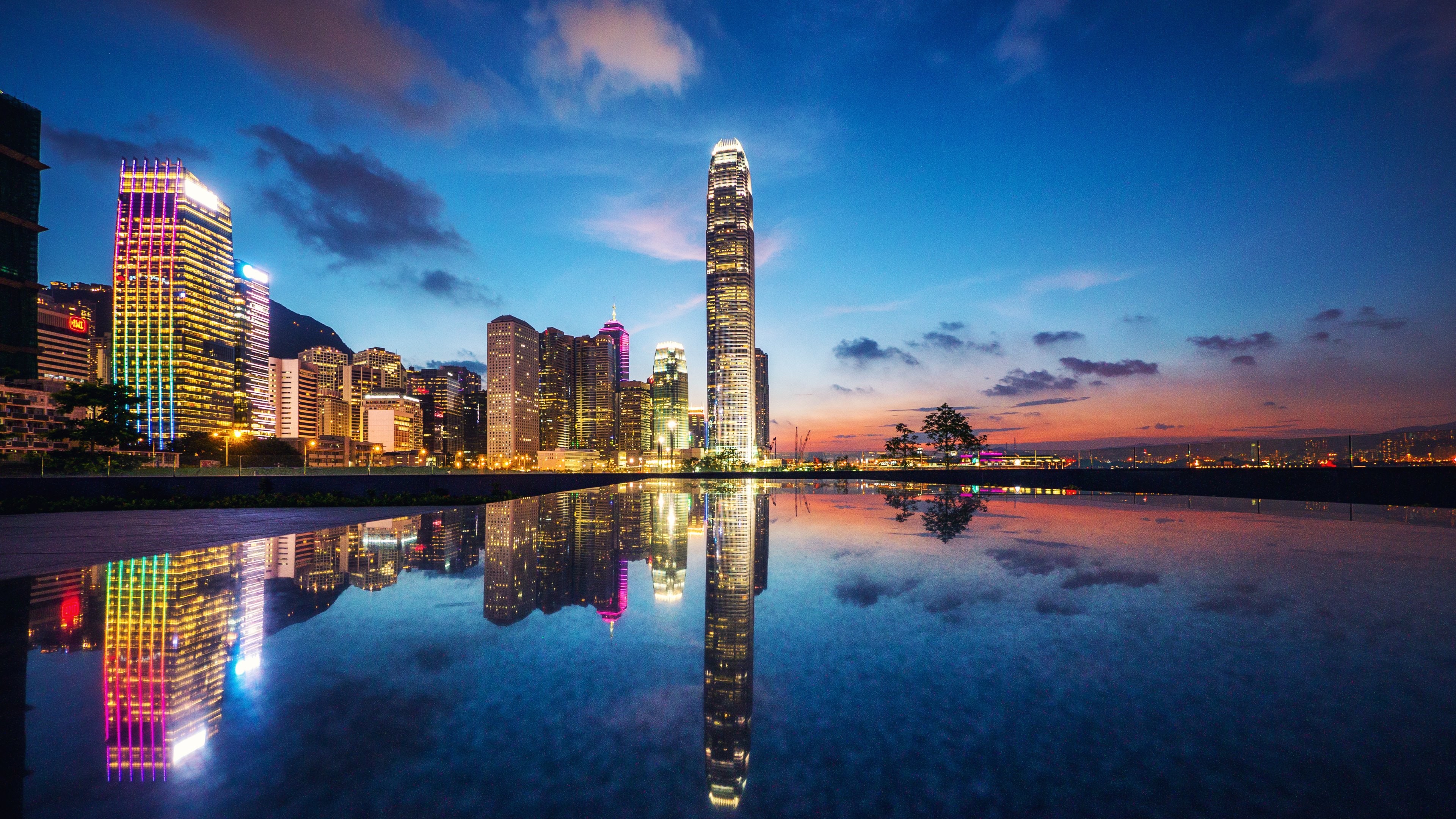 Stunning 4K cityscape of Hong Kong at sunset, with vibrant city lights reflecting in a calm body of water