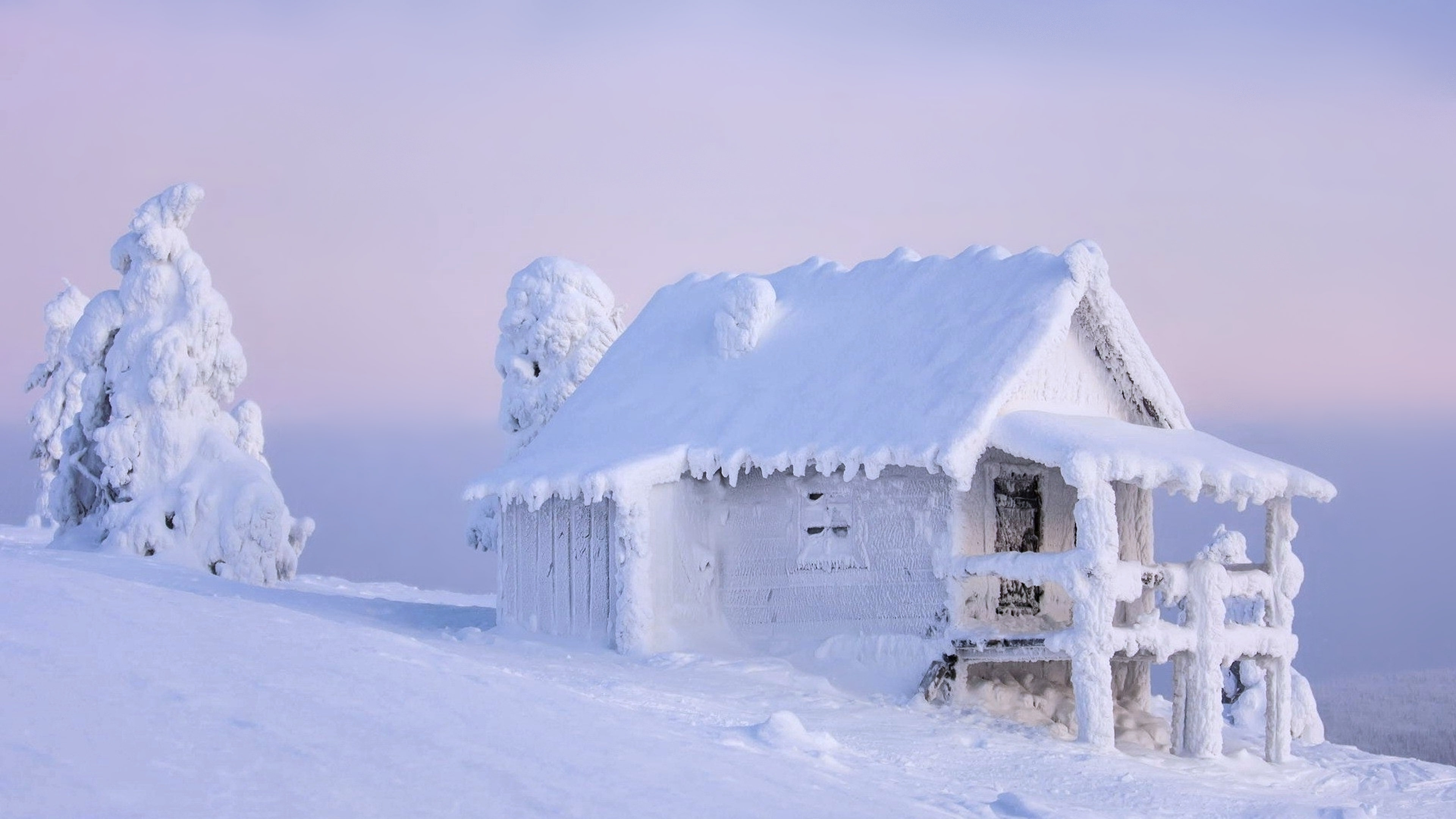 A snow-covered cabin on a hilltop in a winter wonderland, perfect for a 4k winter wallpaper