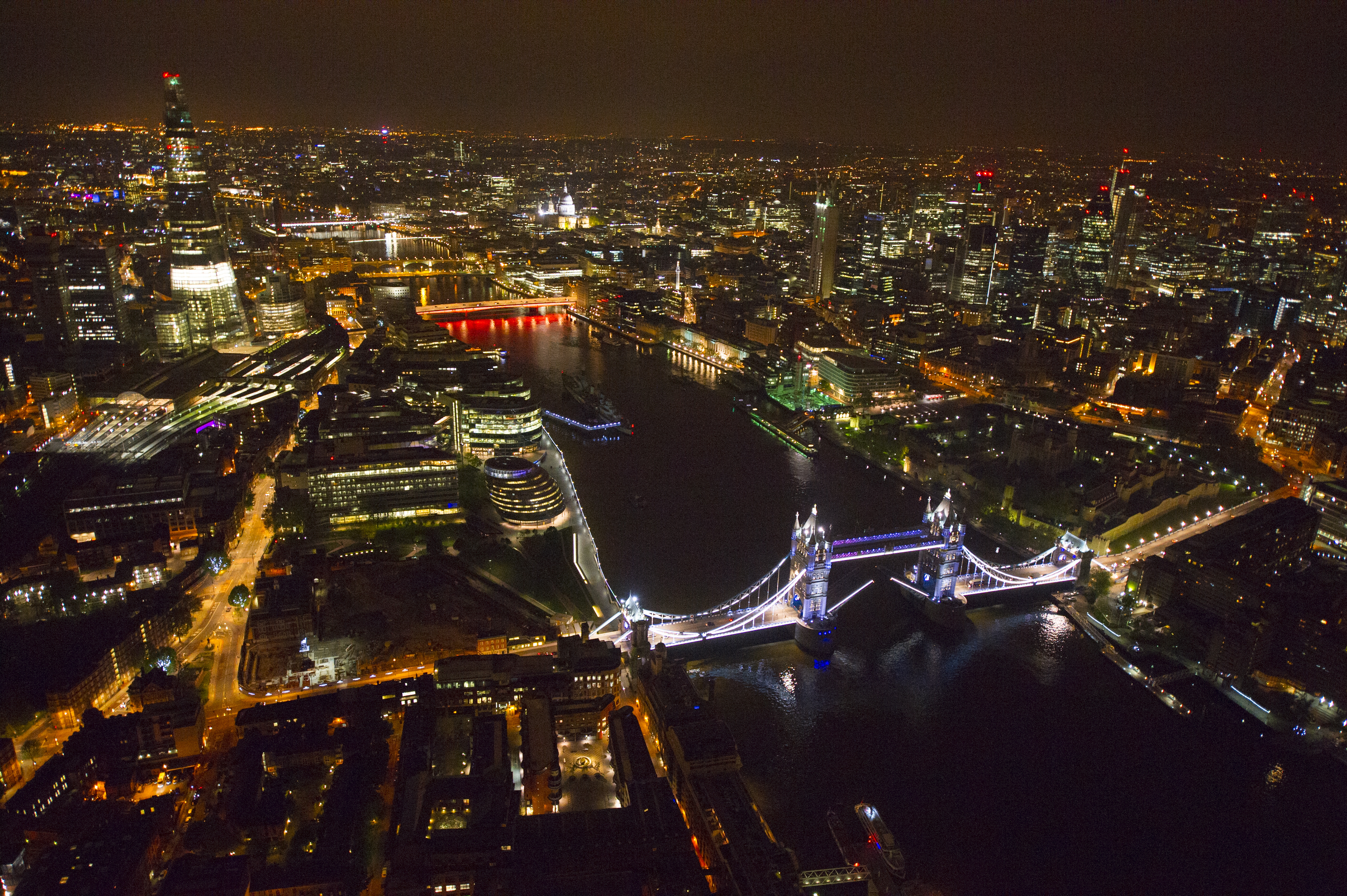 Aerial view of London skyline at night, featuring Tower Bridge and the River Thames