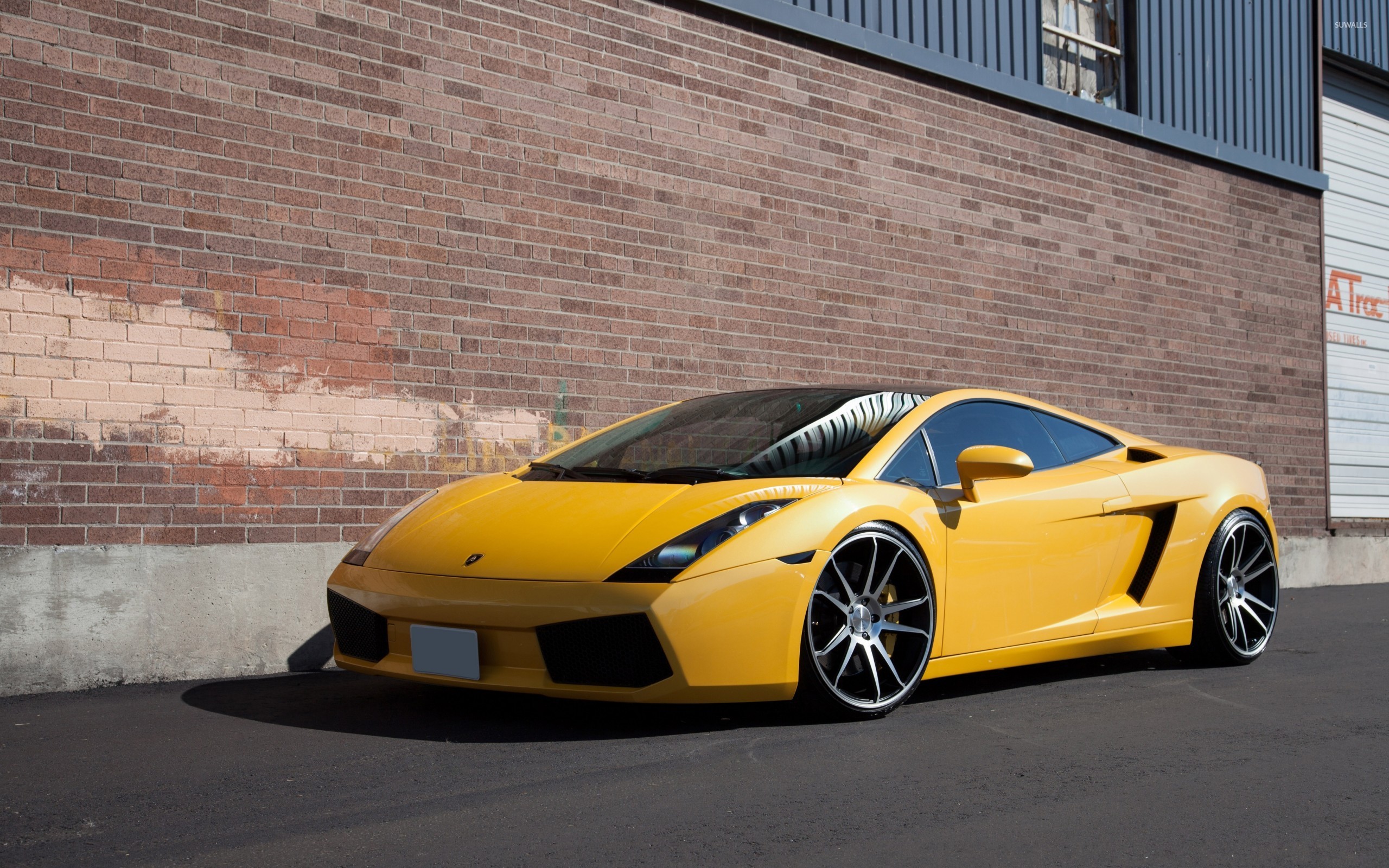 Bright Yellow Lamborghini Gallardo Parked Against Brick Wall