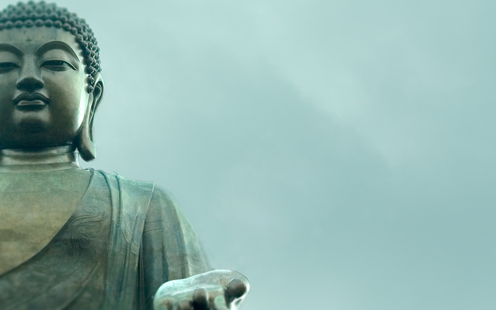 Serene close-up of a bronze Buddha statue against a soft, misty sky