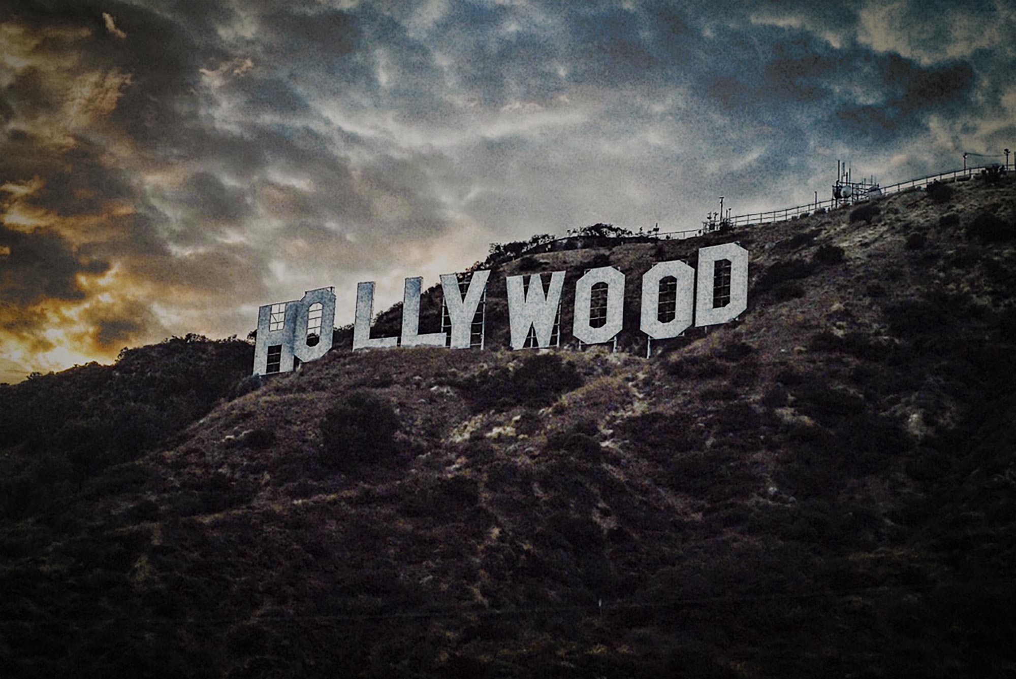 The iconic Hollywood sign stands tall against a dramatic, cloud-filled sky, capturing the essence of the entertainment industry