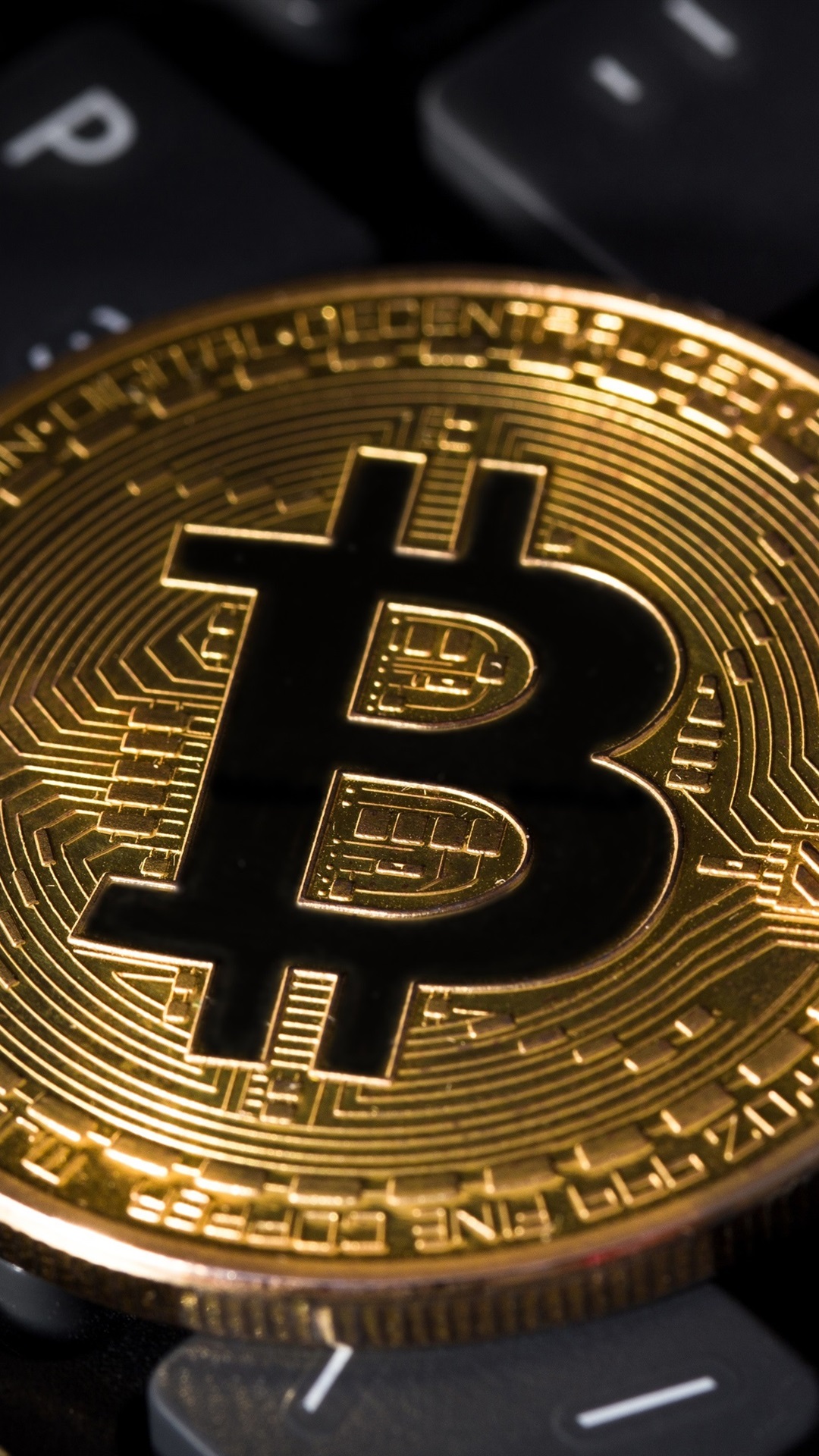 Close-up of a gold Bitcoin cryptocurrency coin resting on a computer keyboard, symbolizing the digital economy and online finance