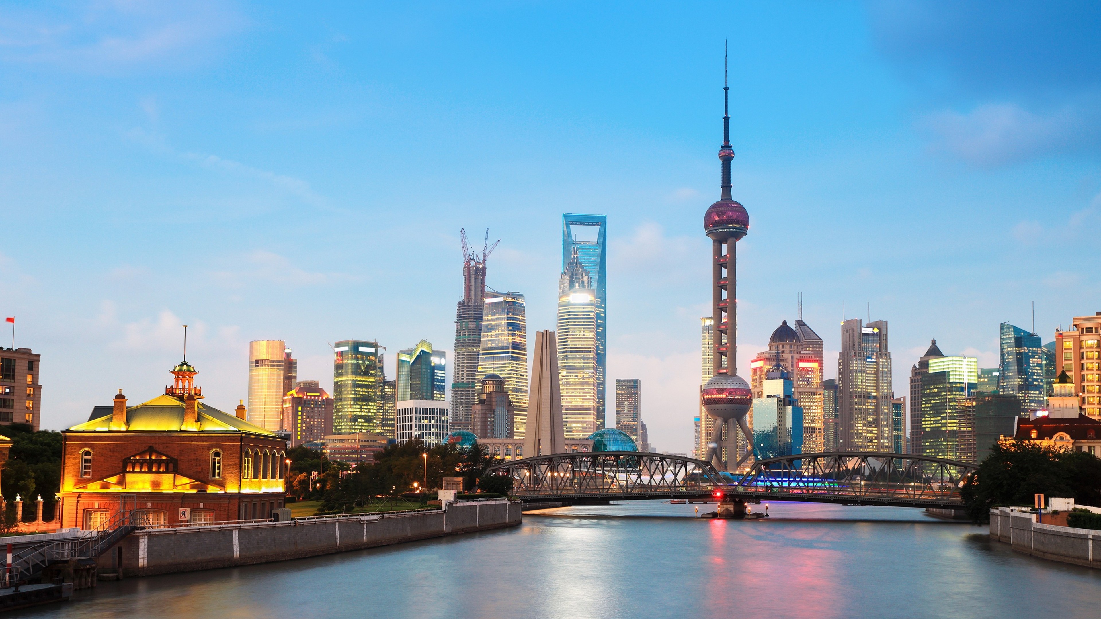 A breathtaking panorama of the Shanghai skyline at sunset, featuring the iconic Oriental Pearl Tower, modern skyscrapers, and the historic Bund district along the Huangpu River