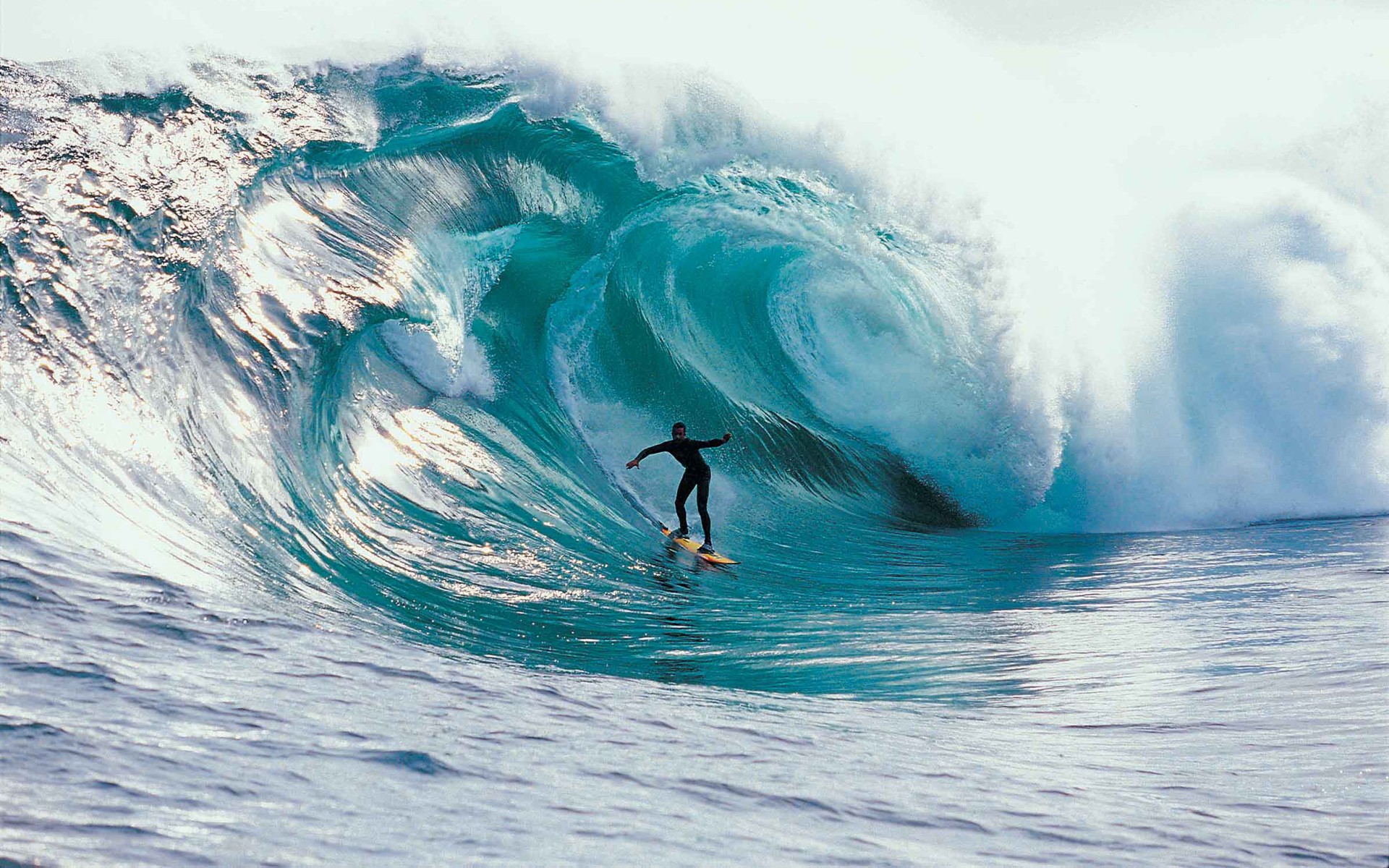 A surfer rides a massive, curling wave in the ocean, showcasing the thrill and power of surfing