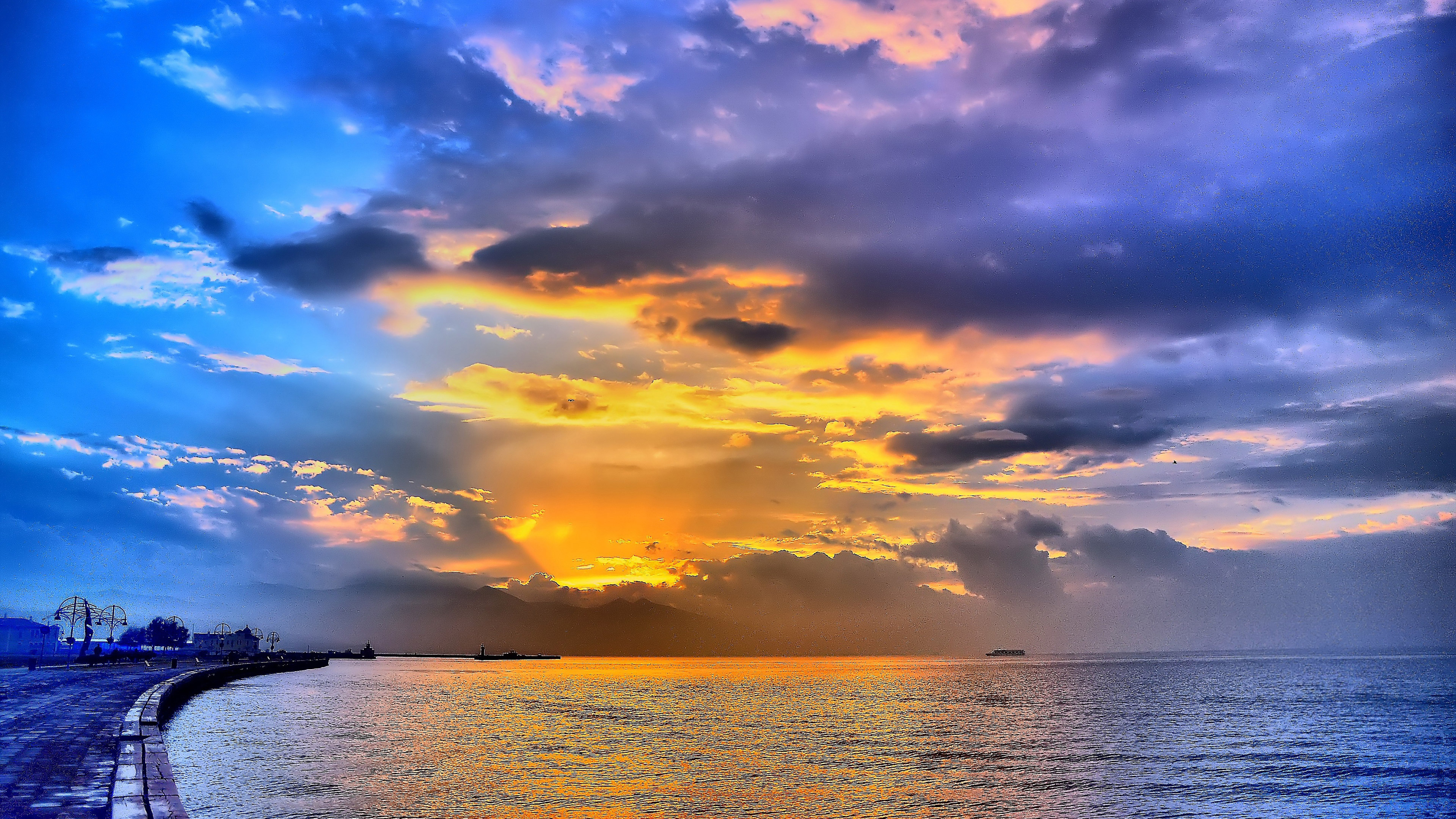 A breathtaking sunset over a tranquil sea, with vibrant colors painting the sky and clouds