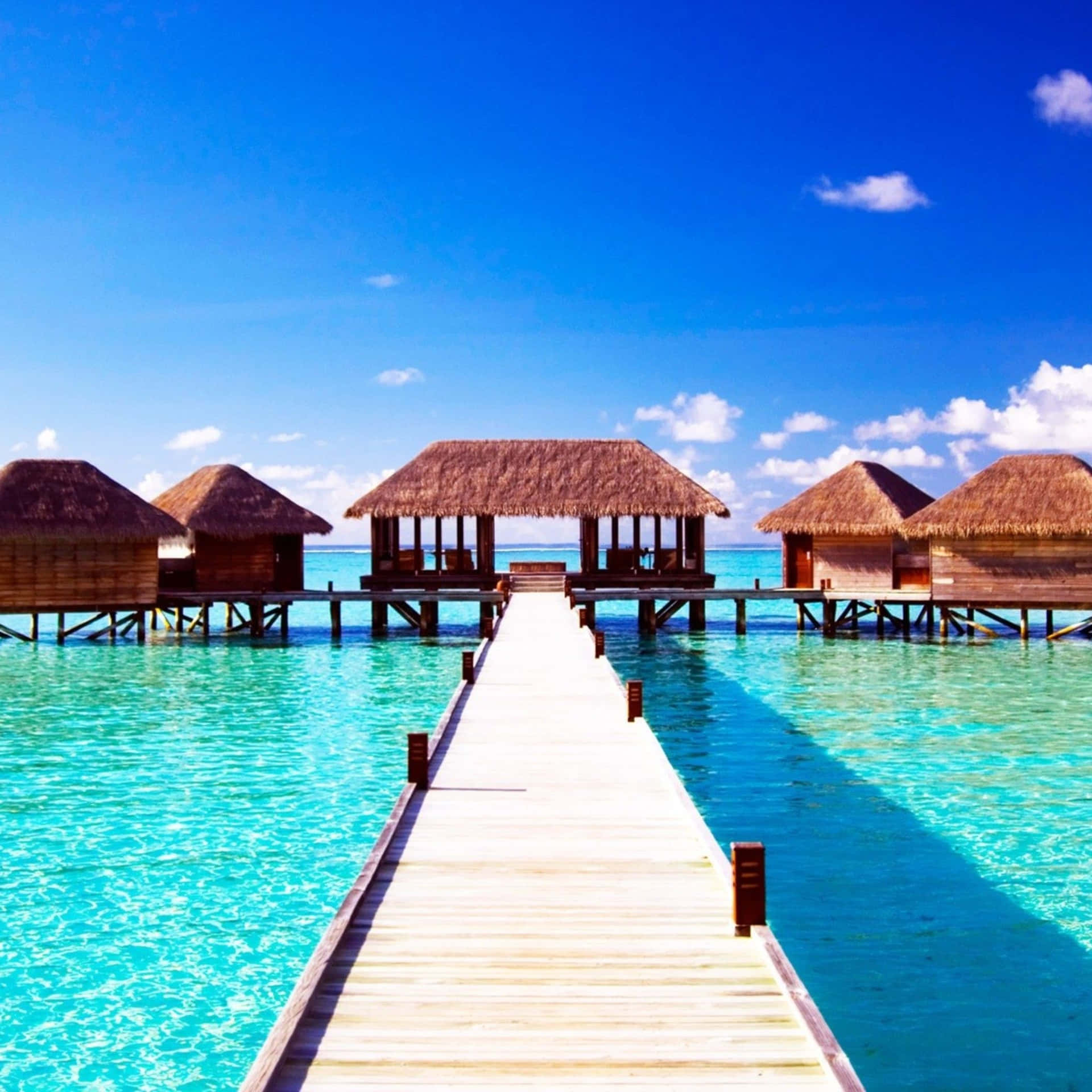 A Pier Leading To Some Huts Dope Wallpaper