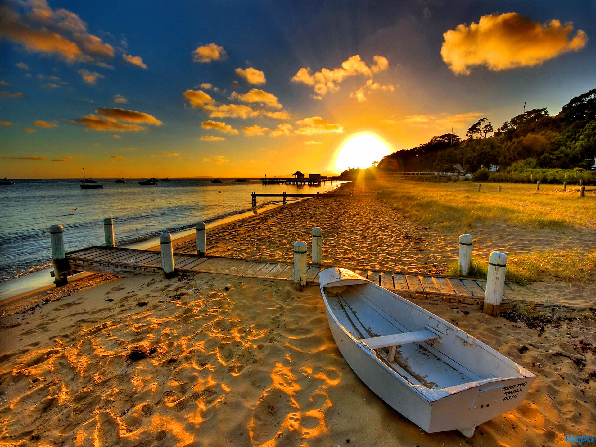 Serene sunset at a sandy beach with a small boat in the foreground, perfect for a beach computer background