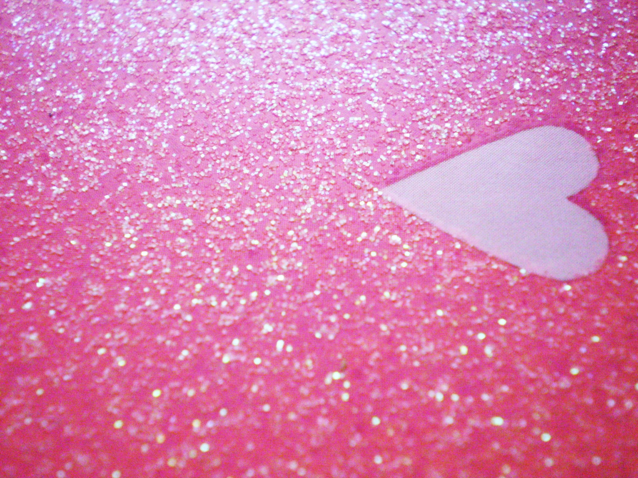 A pink glitter background with a light purple heart shape in the center