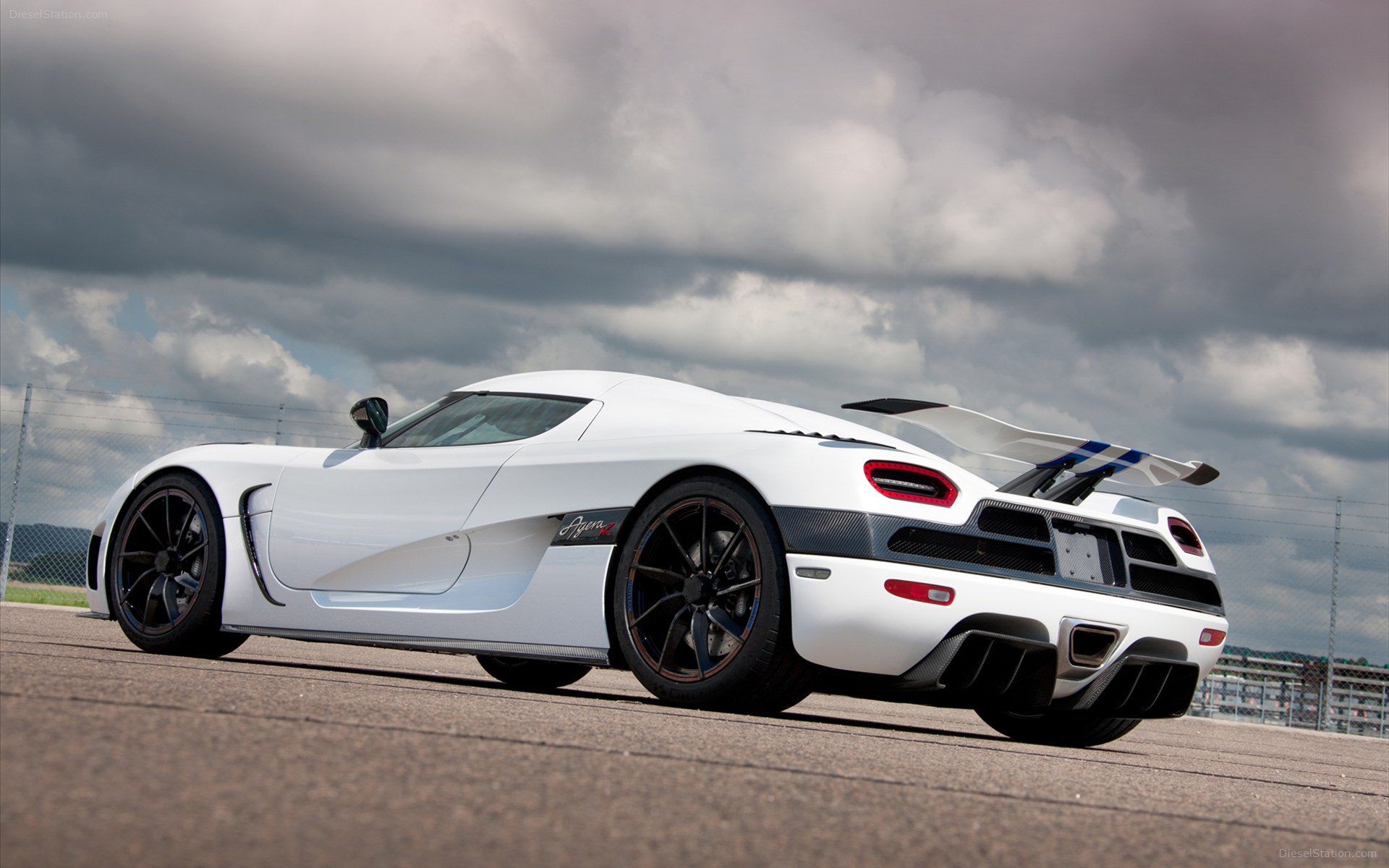 A white Koenigsegg Agera R sports car parked on a tarmac under a cloudy sky