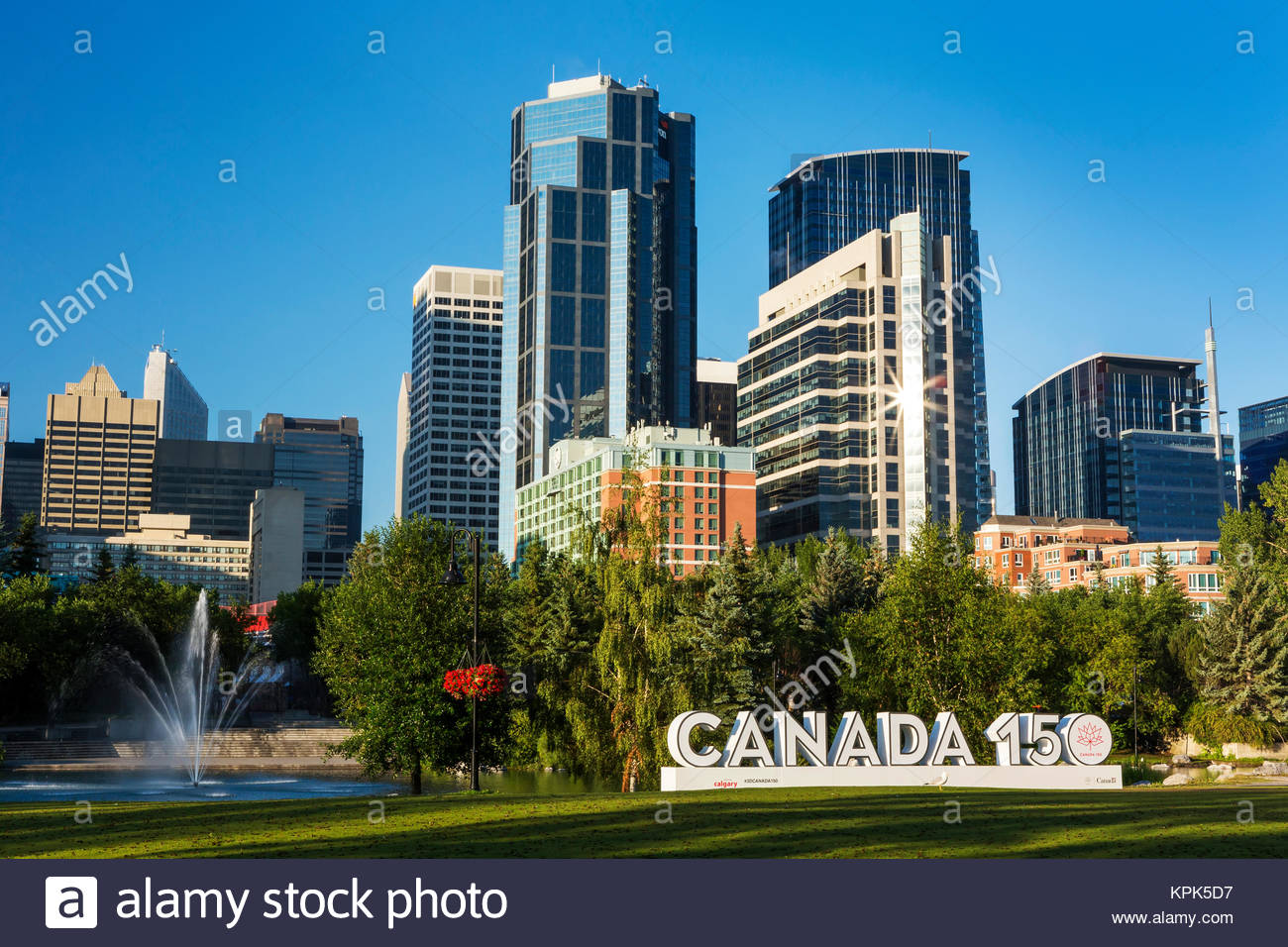 Canada 150 signage in city park with Calgary building towers in
