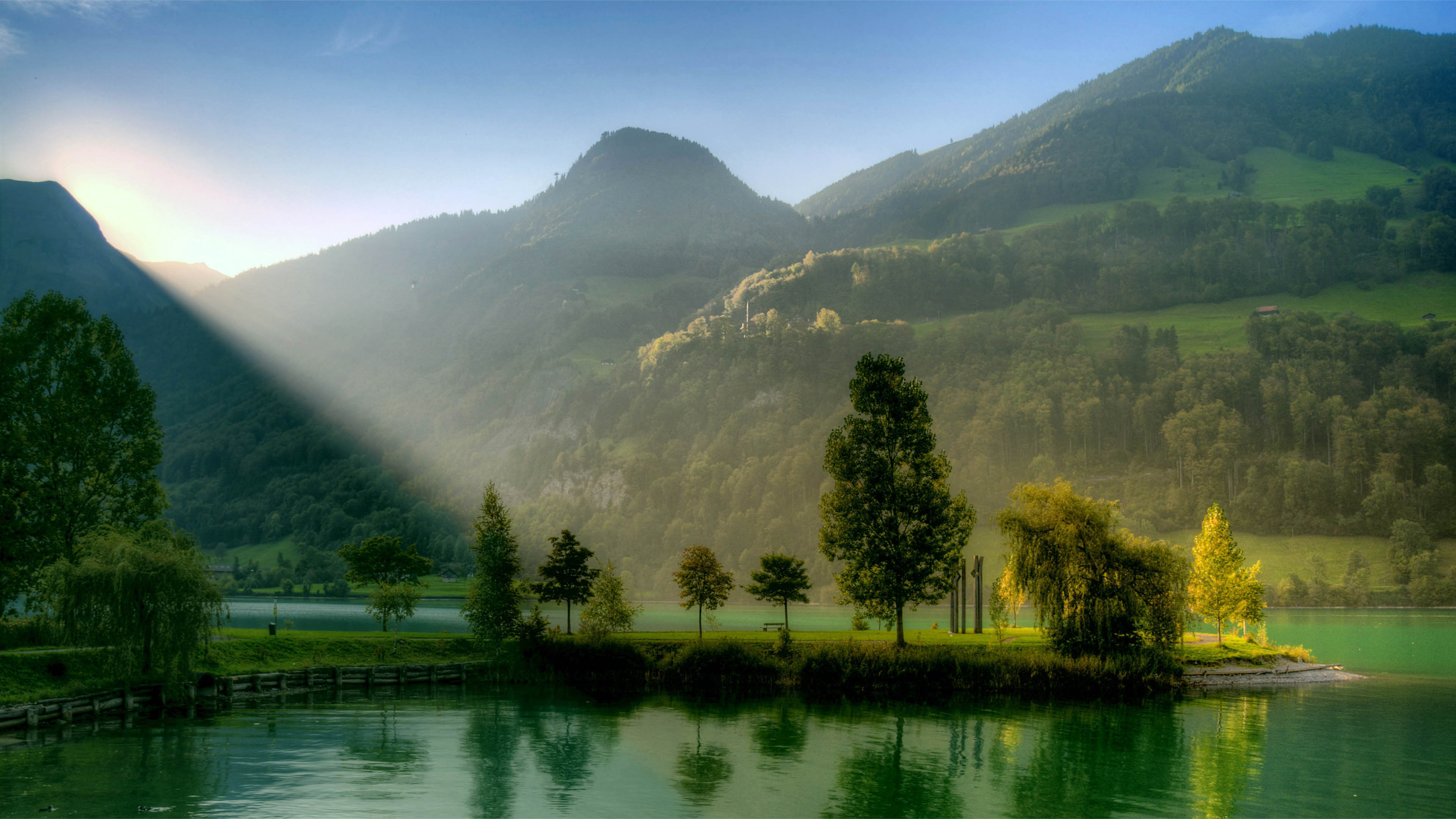 Sunrise over a serene lake with mountains in the background, perfect for a scenic computer wallpaper
